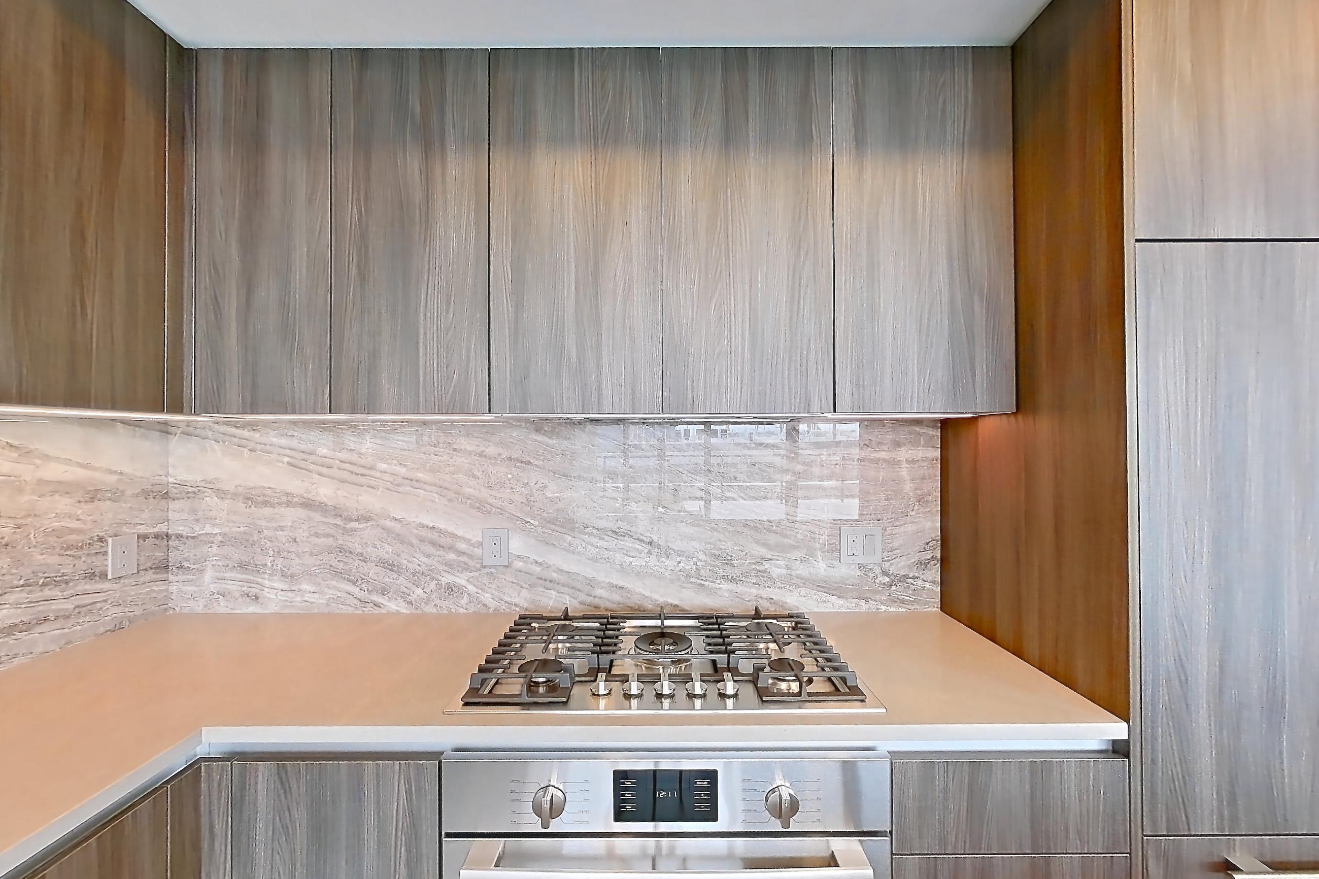 Kitchen with cooktop, gas cooktop, light stone countertops, light wood-finish flooring, oven/range, stainless steel appliances, and wood-finish flooring, Apartment 1709 at Zephyr
