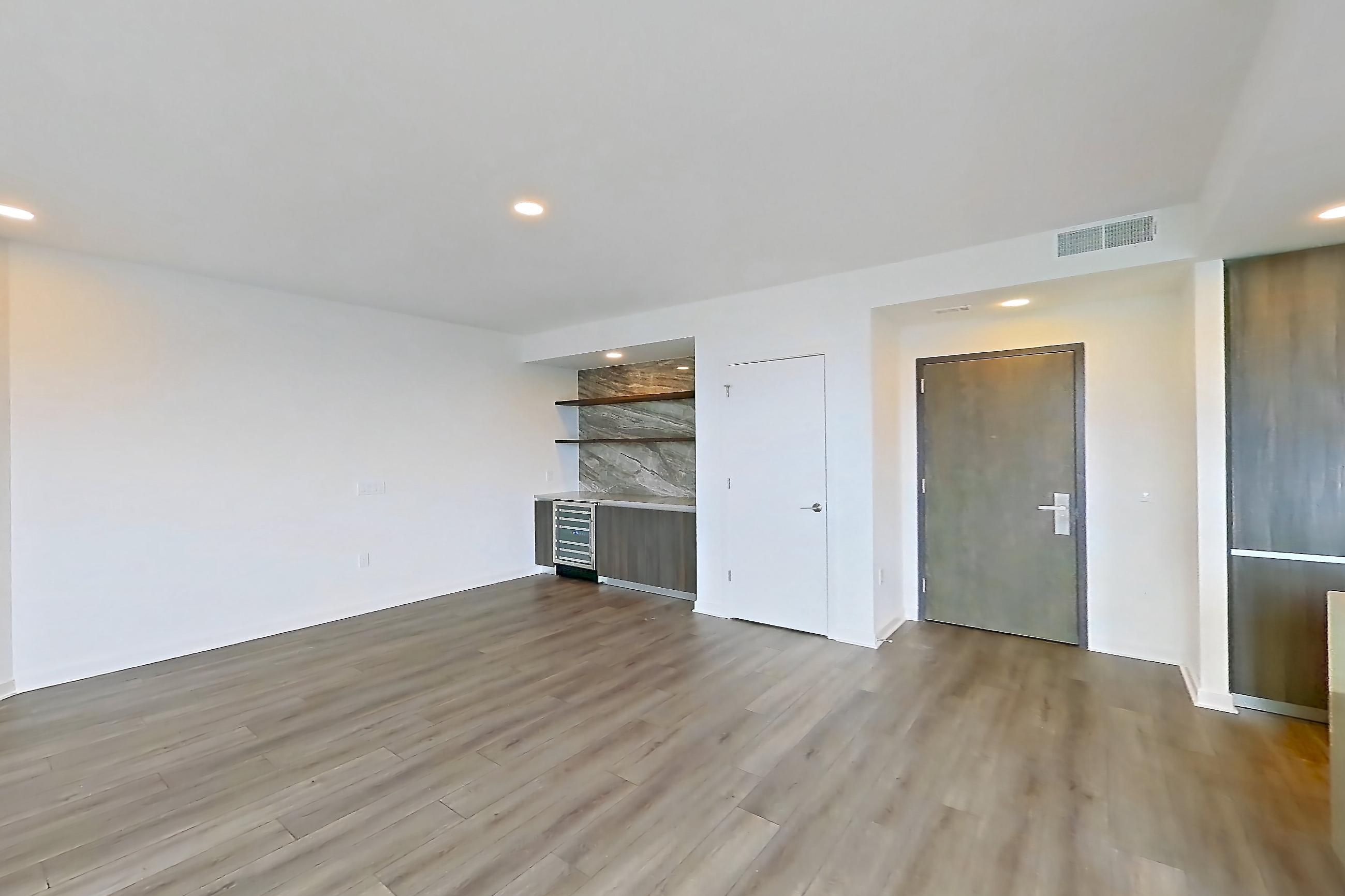 Living room with light wood-finish flooring and wet/dry bar, Apartment 1712 at Zephyr