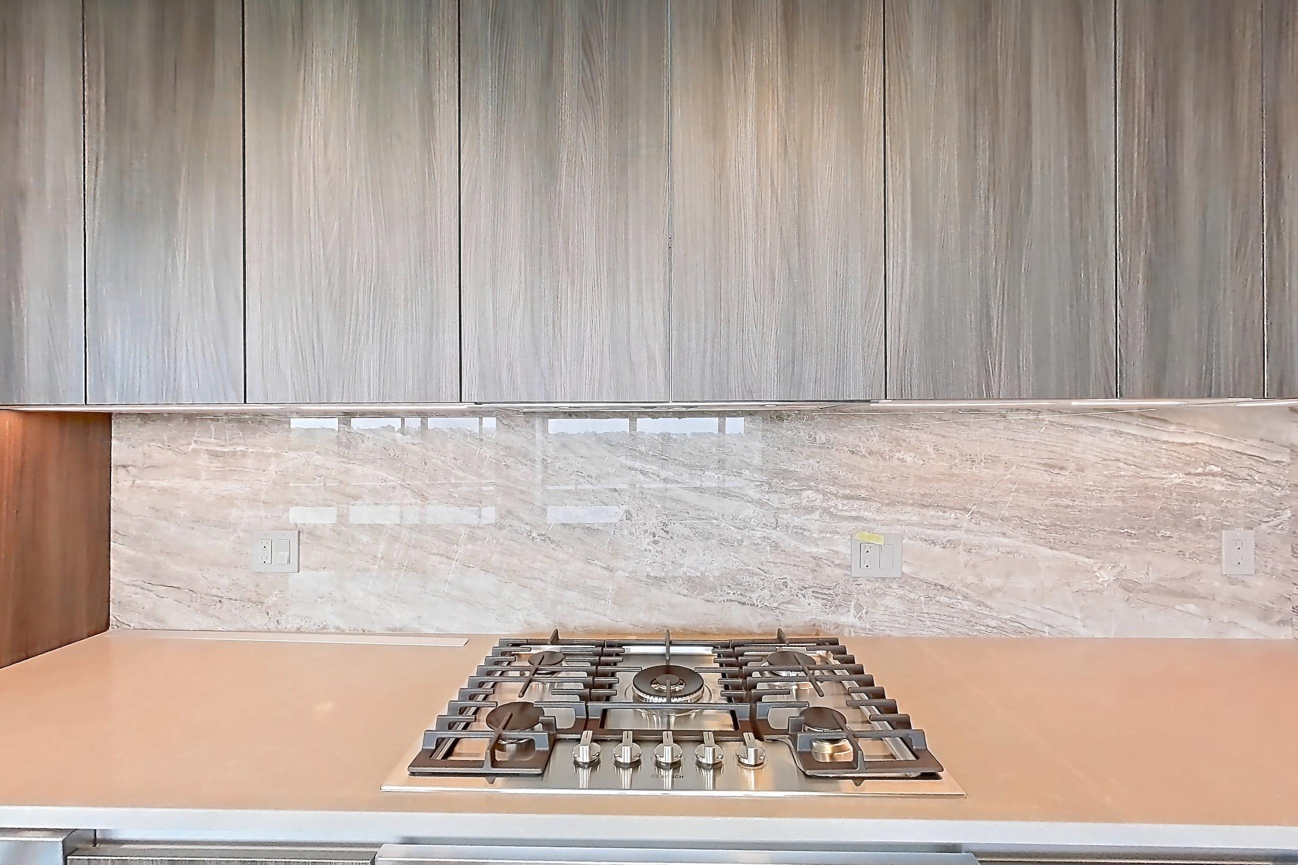 Kitchen with cooktop, gas cooktop, light stone countertops, light wood-finish flooring, oven/range, and stainless steel appliances, Apartment 1701 at Zephyr