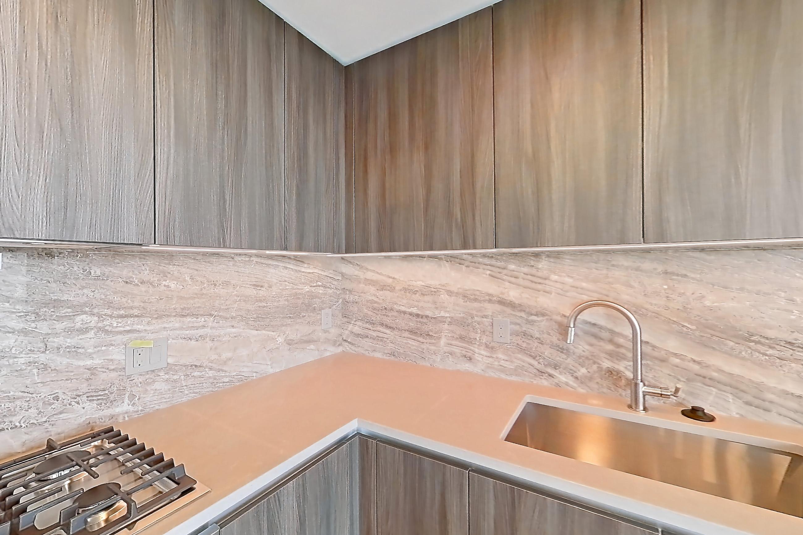 Kitchen with cooktop, gas cooktop, light stone countertops, light wood-finish flooring, oven/range, and stainless steel appliances, Apartment 1701 at Zephyr
