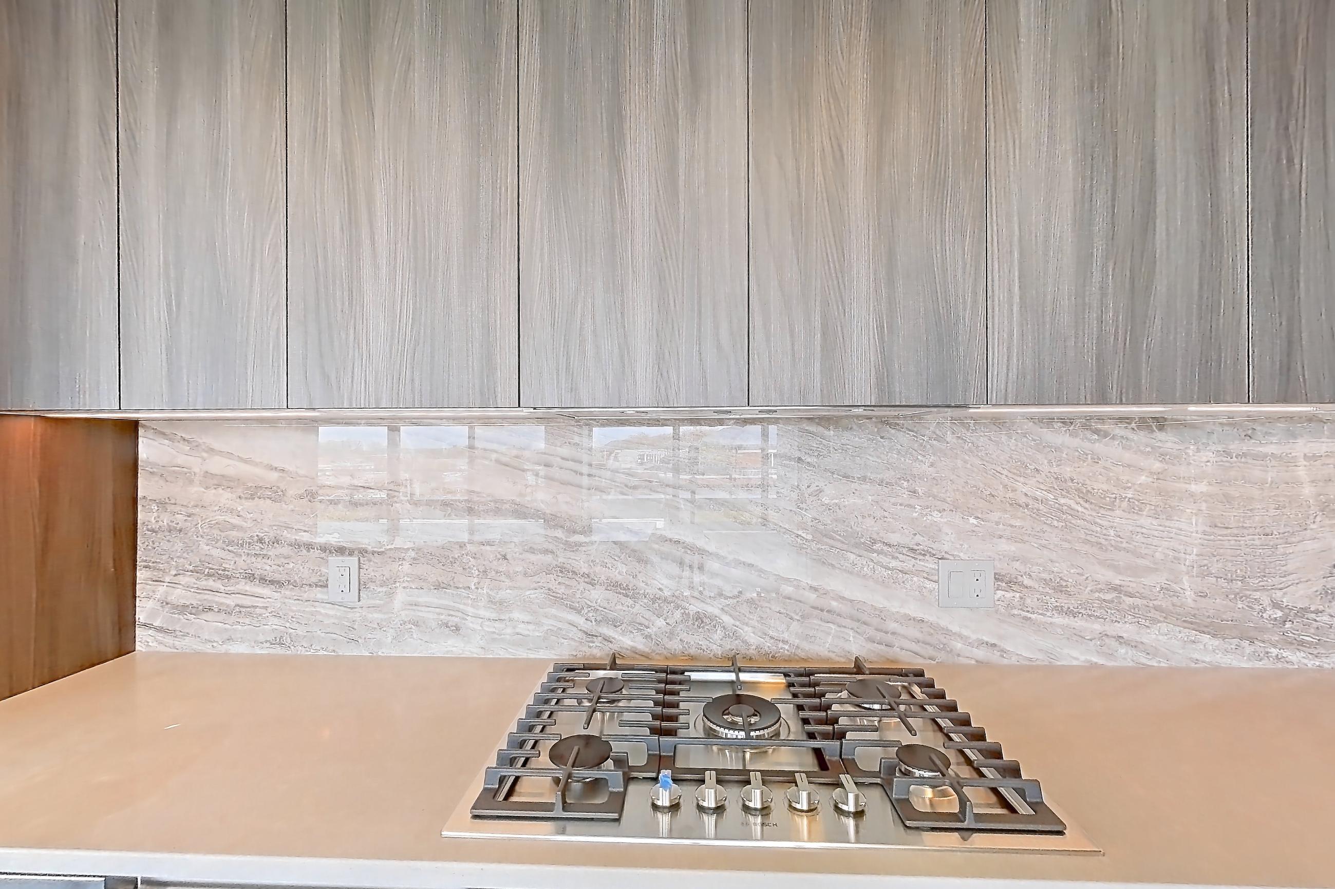 Kitchen with cooktop, gas cooktop, light stone countertops, light wood-finish flooring, oven/range, and stainless steel appliances, Apartment 1705 at Zephyr