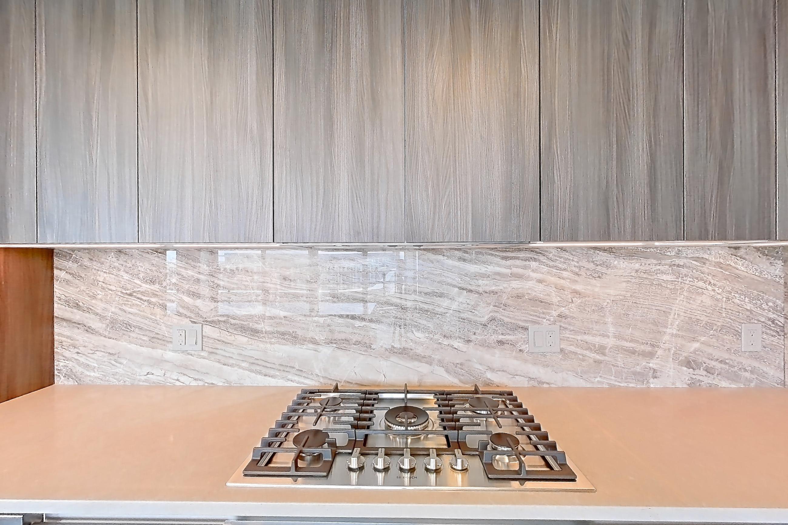 Kitchen with cooktop, gas cooktop, light stone countertops, light wood-finish flooring, oven/range, and stainless steel appliances, Apartment 1711 at Zephyr