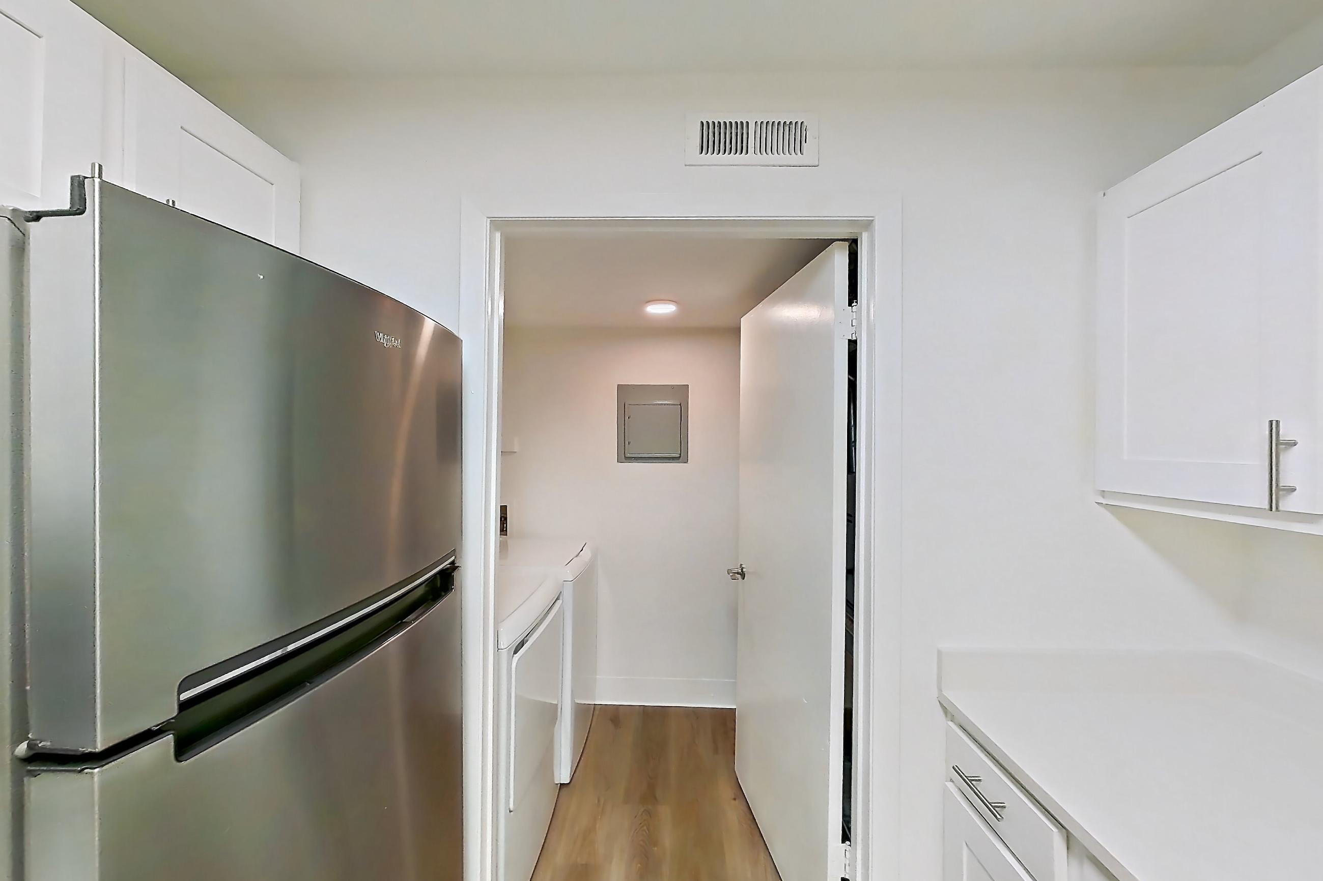 Kitchen with dishwasher, electric range, in-unit laundry, light countertops, light wood-finish flooring, oven/range, range hood, refrigerator, and stainless steel appliances, Apartment 08S at James Pointe