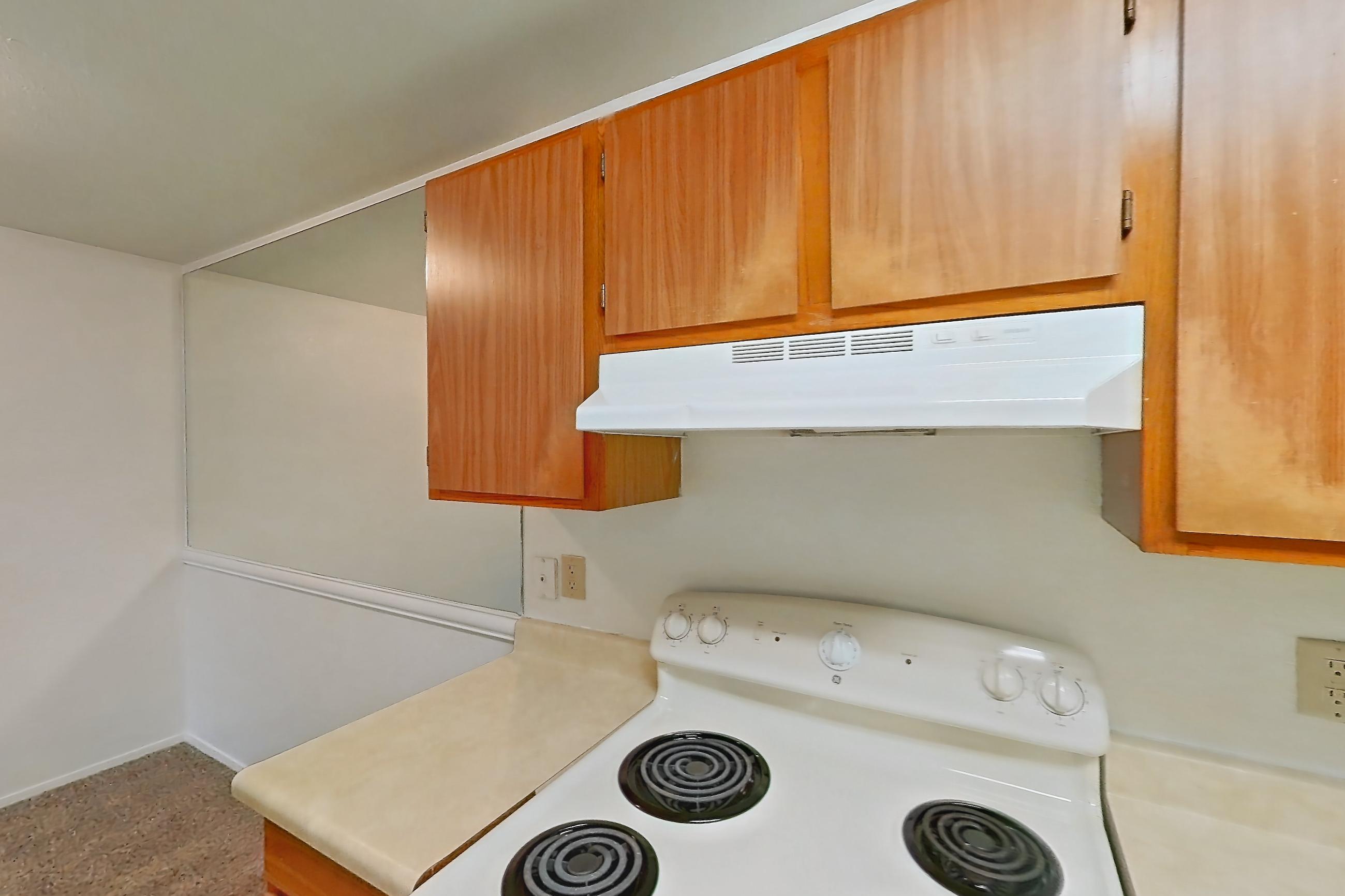 Kitchen with dishwasher, electric range, light countertops, light wood-finish flooring, oven/range, refrigerator, and white appliances, Apartment 12U at James Pointe