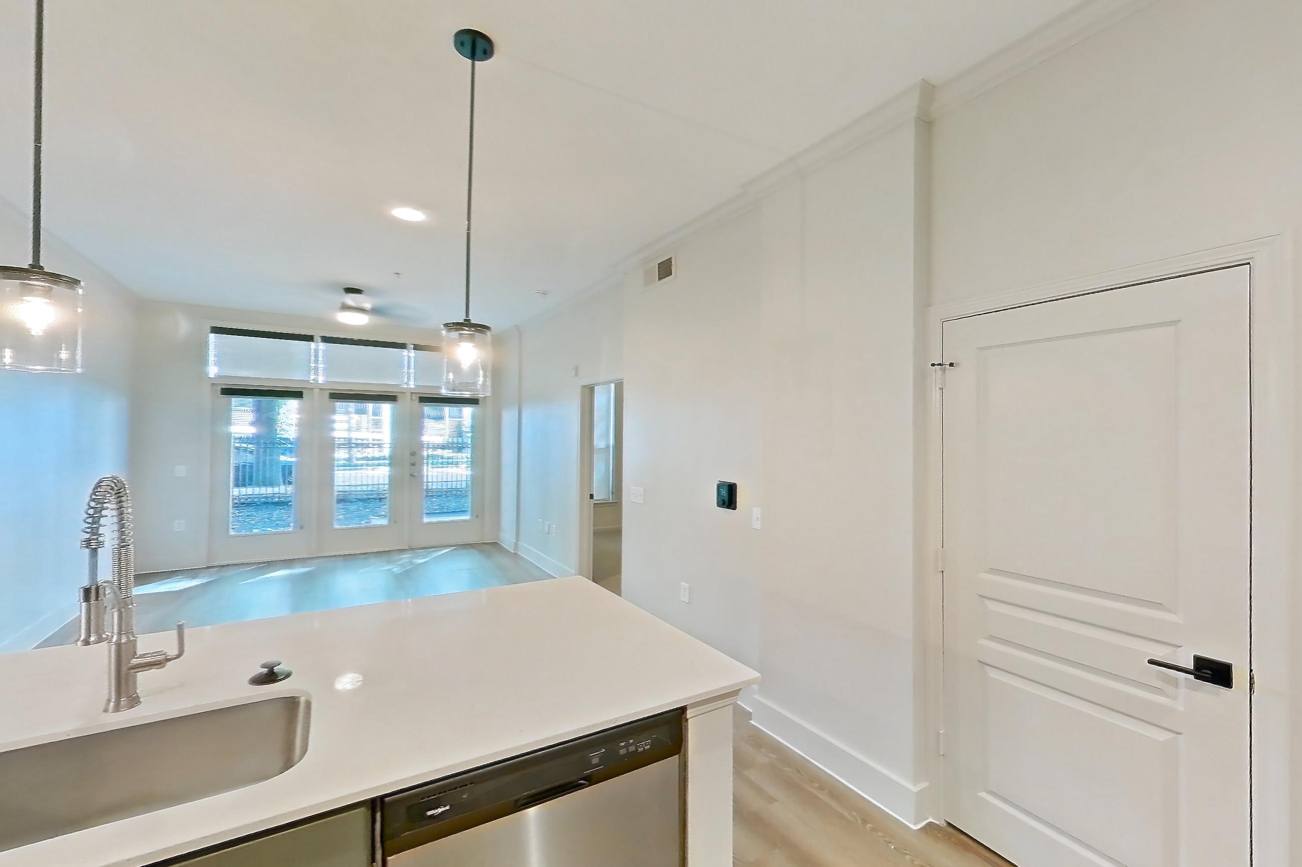 Kitchen with dishwasher, electric range, light countertops, light stone countertops, light wood-finish flooring, microwave, oven/range, refrigerator, and stainless steel appliances, Apartment 1011 at La Maison at River Oaks