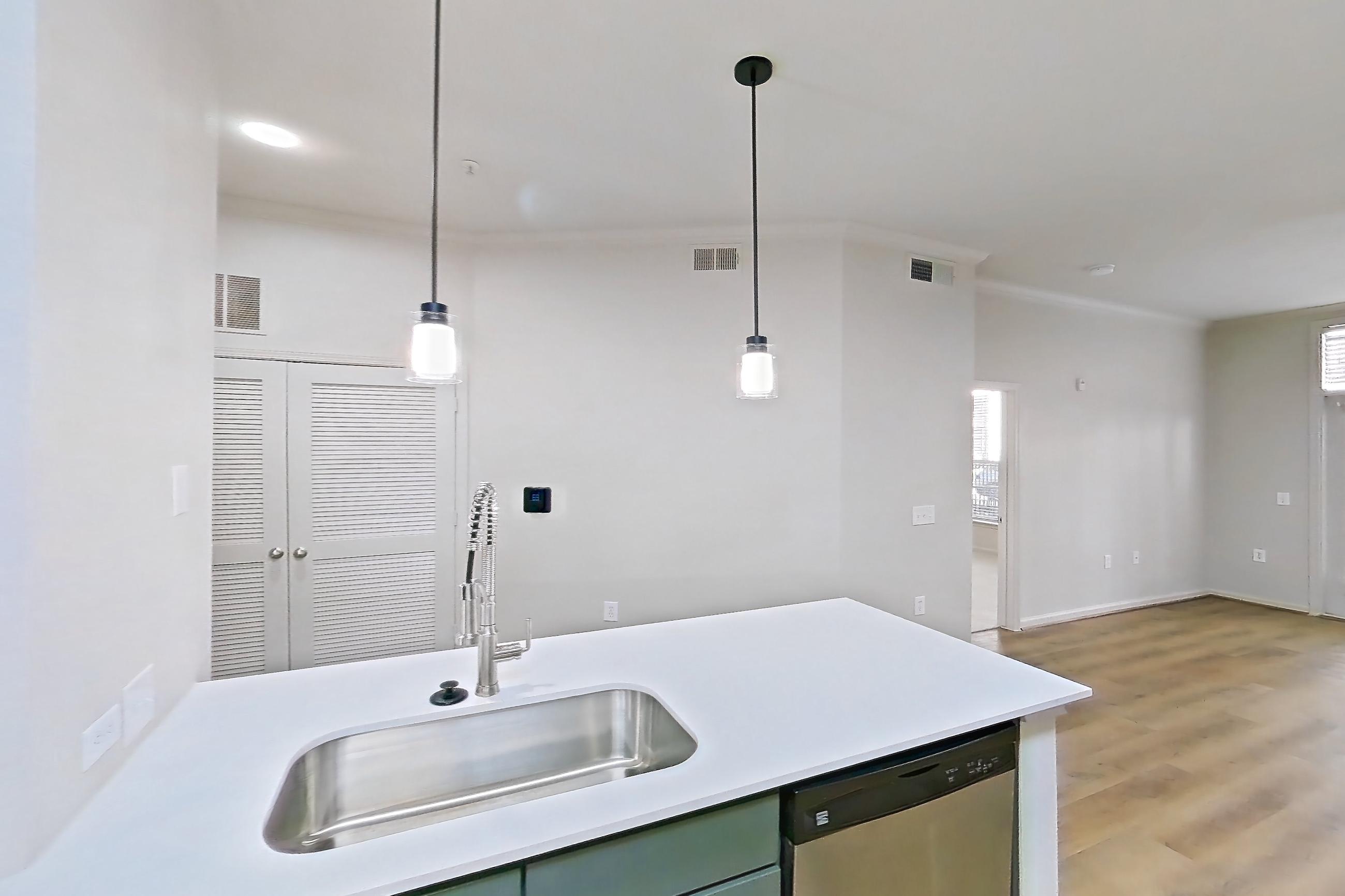 Kitchen with dishwasher, electric range, light countertops, light stone countertops, light wood-finish flooring, microwave, oven/range, refrigerator, and stainless steel appliances, Apartment 1015 at La Maison at River Oaks