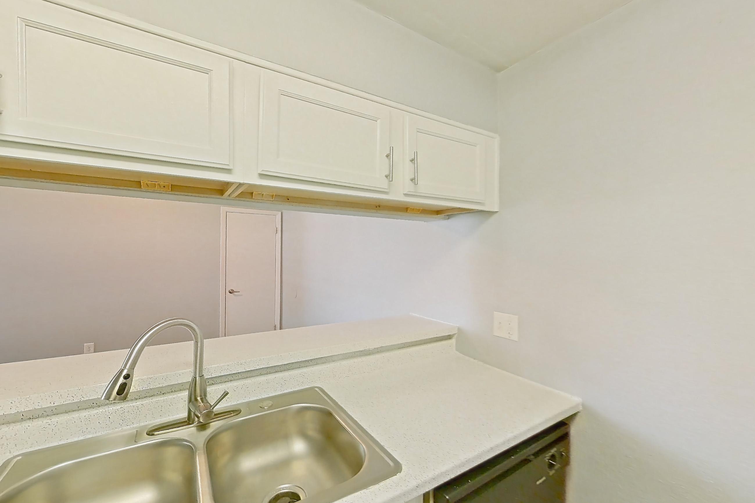 Kitchen with black appliances, dark wood-finish flooring, dishwasher, electric range, fireplace, light countertops, light stone countertops, light wood-finish flooring, oven/range, and refrigerator, Apartment 190 at Eleven600 Apartments