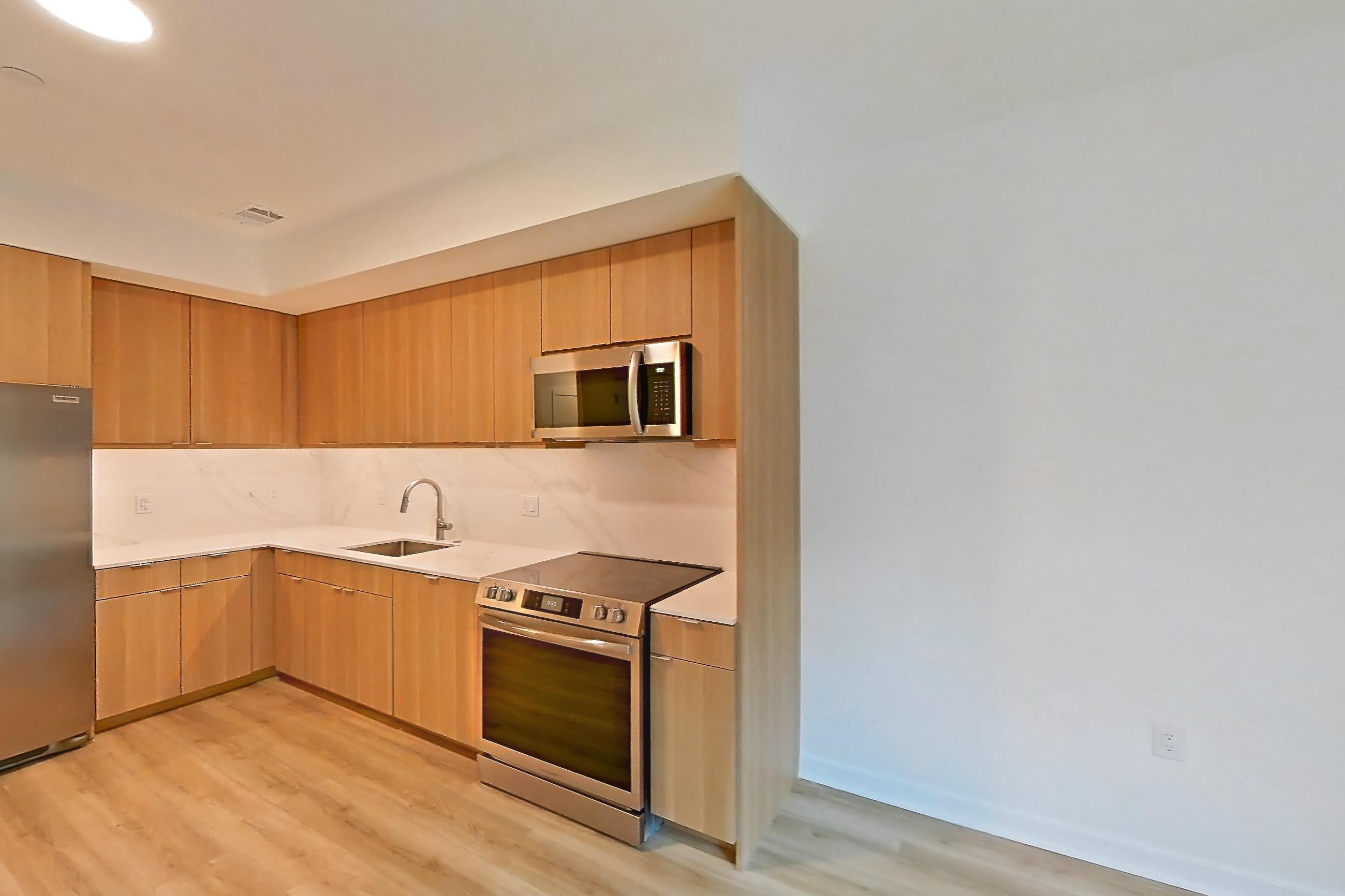 Living room with light countertops, light wood-finish flooring, microwave, oven/range, and stainless steel appliances, Apartment 442 at Residences at Mazza