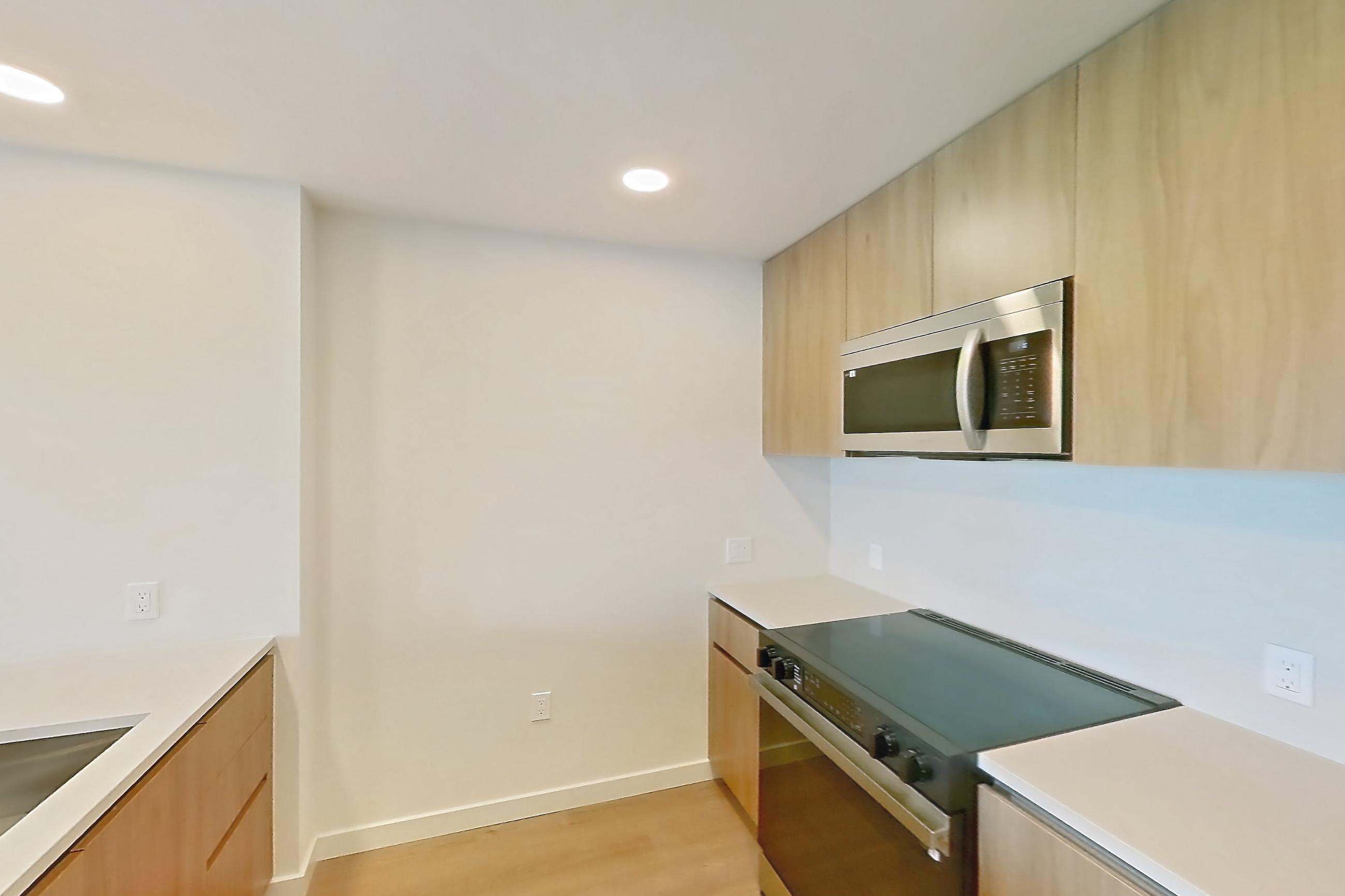 Kitchen with black appliances, dishwasher, electric range, light countertops, light wood-finish flooring, microwave, oven/range, and stainless steel appliances, Apartment 258 at Rowyn