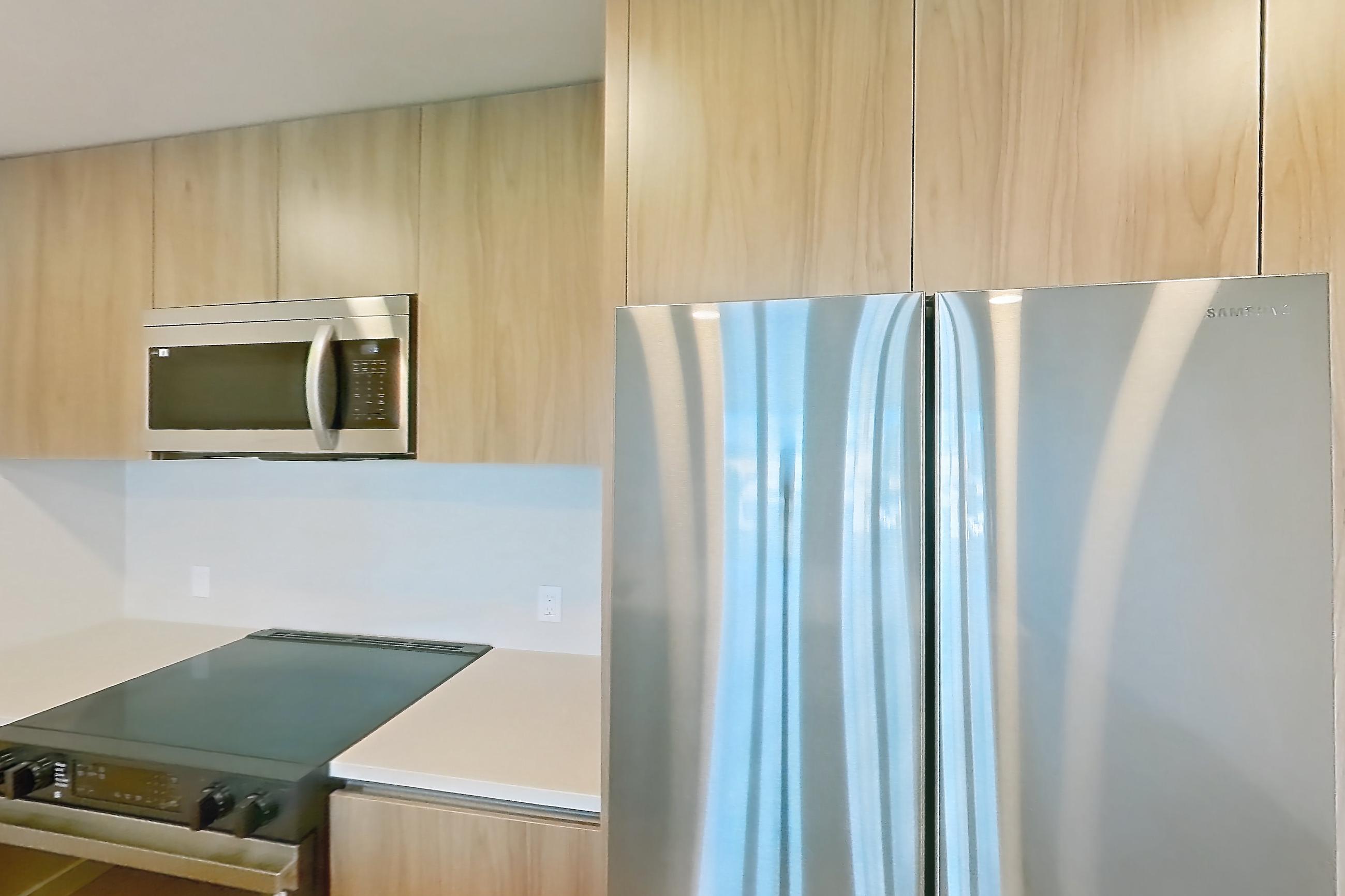 Kitchen with black appliances, dishwasher, electric range, light countertops, light wood-finish flooring, microwave, oven/range, and stainless steel appliances, Apartment 258 at Rowyn