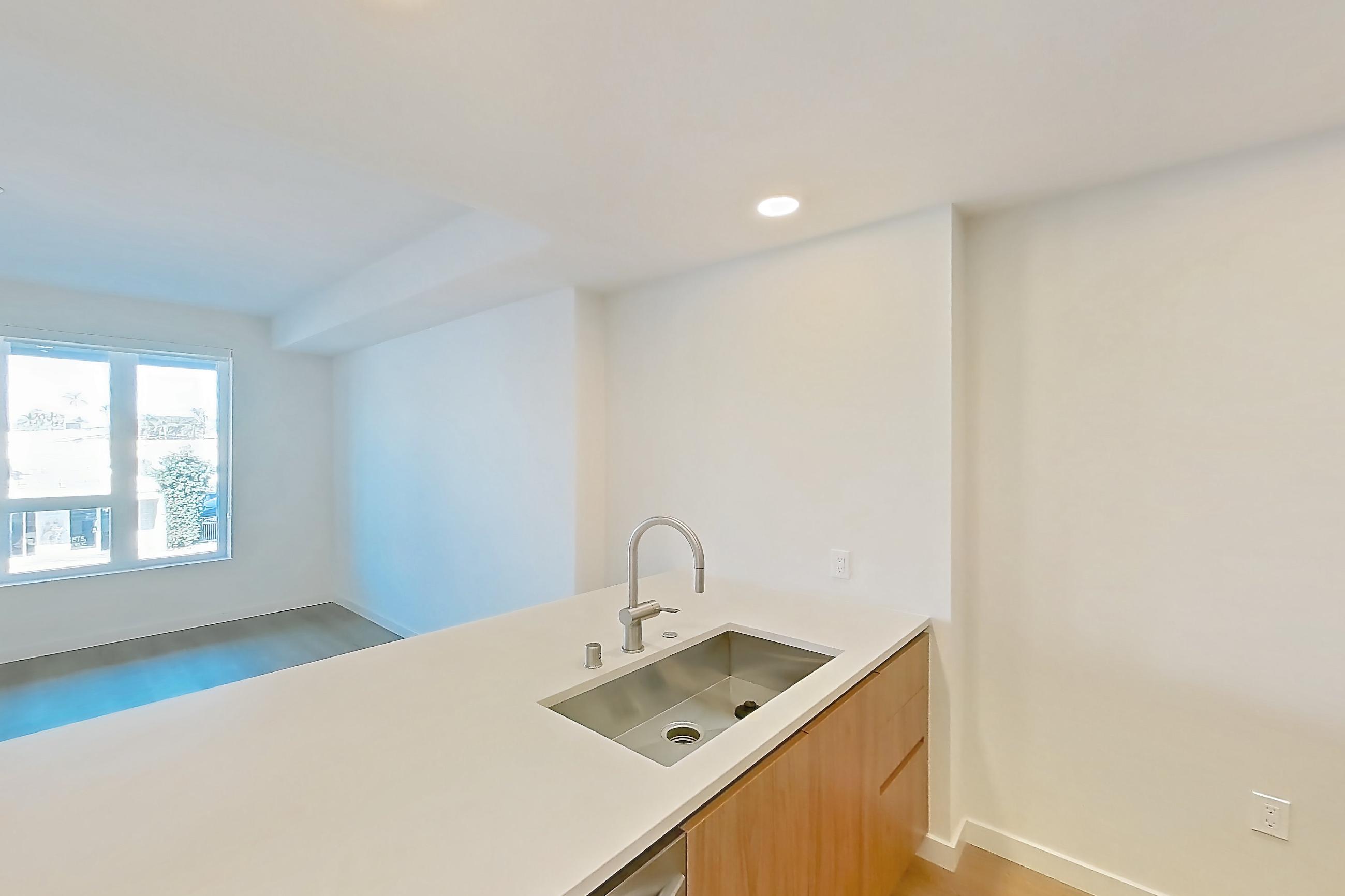 Kitchen with black appliances, dishwasher, electric range, light countertops, light wood-finish flooring, microwave, oven/range, and stainless steel appliances, Apartment 258 at Rowyn