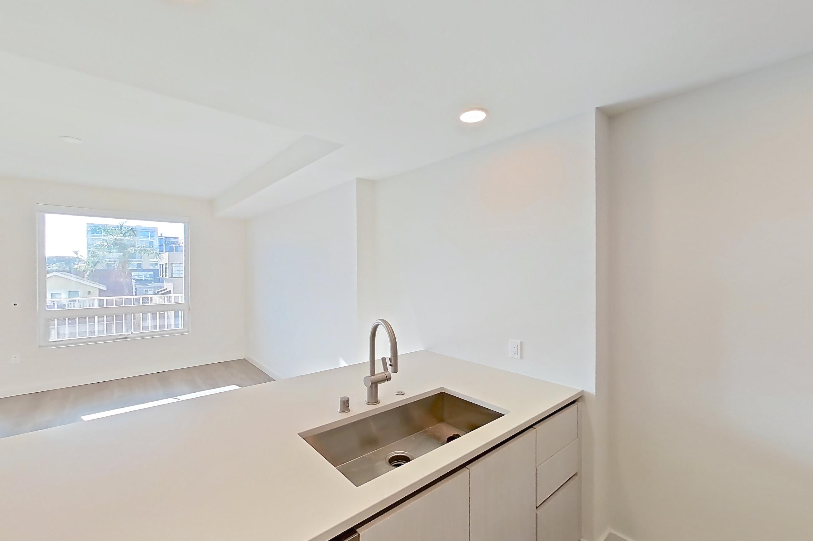 Kitchen with black appliances, dishwasher, electric range, light countertops, light stone countertops, light wood-finish flooring, microwave, oven/range, refrigerator, and stainless steel appliances, Apartment 342 at Rowyn