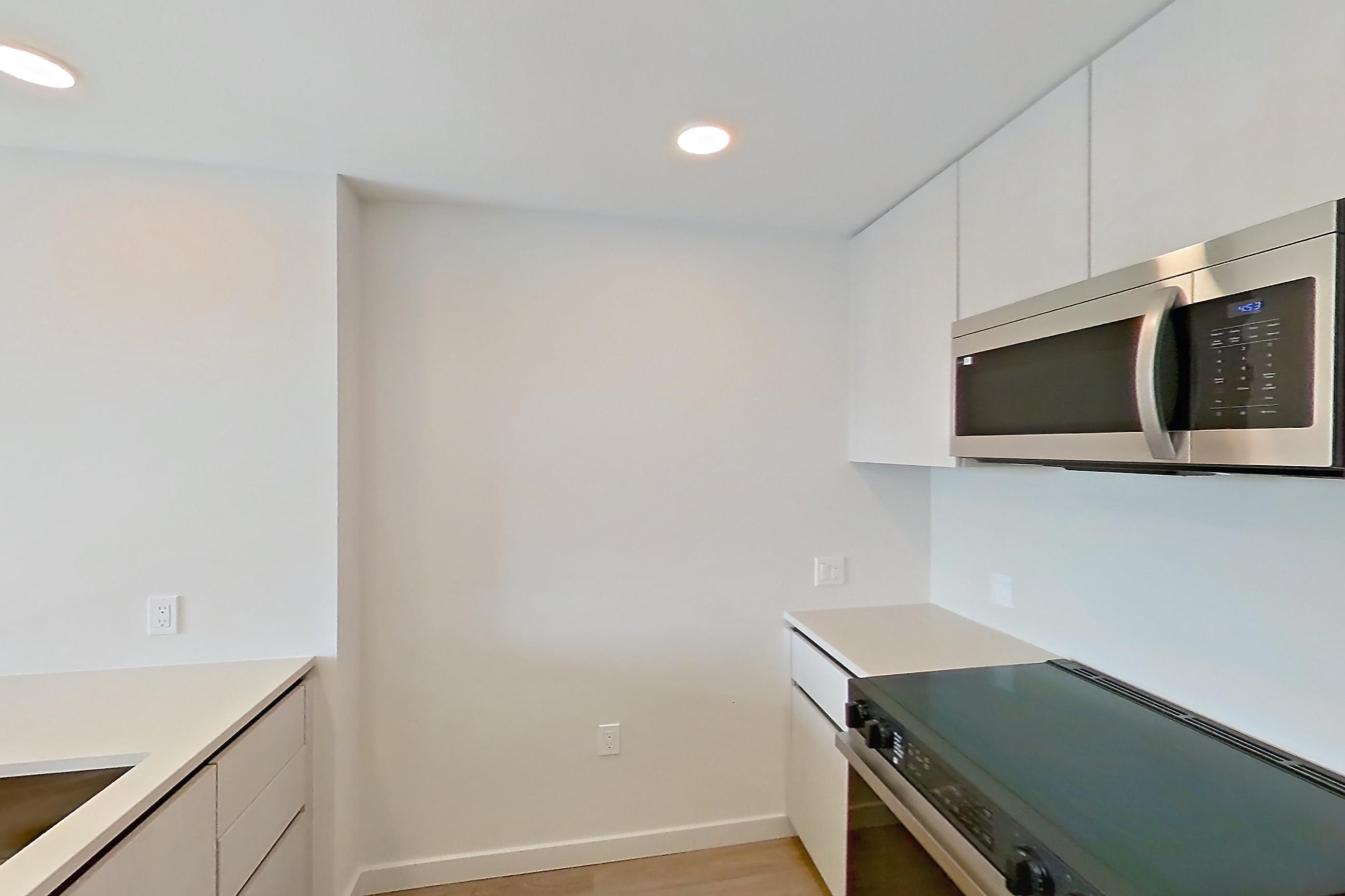 Kitchen with black appliances, dishwasher, electric range, light countertops, light stone countertops, light wood-finish flooring, microwave, oven/range, refrigerator, and stainless steel appliances, Apartment 342 at Rowyn