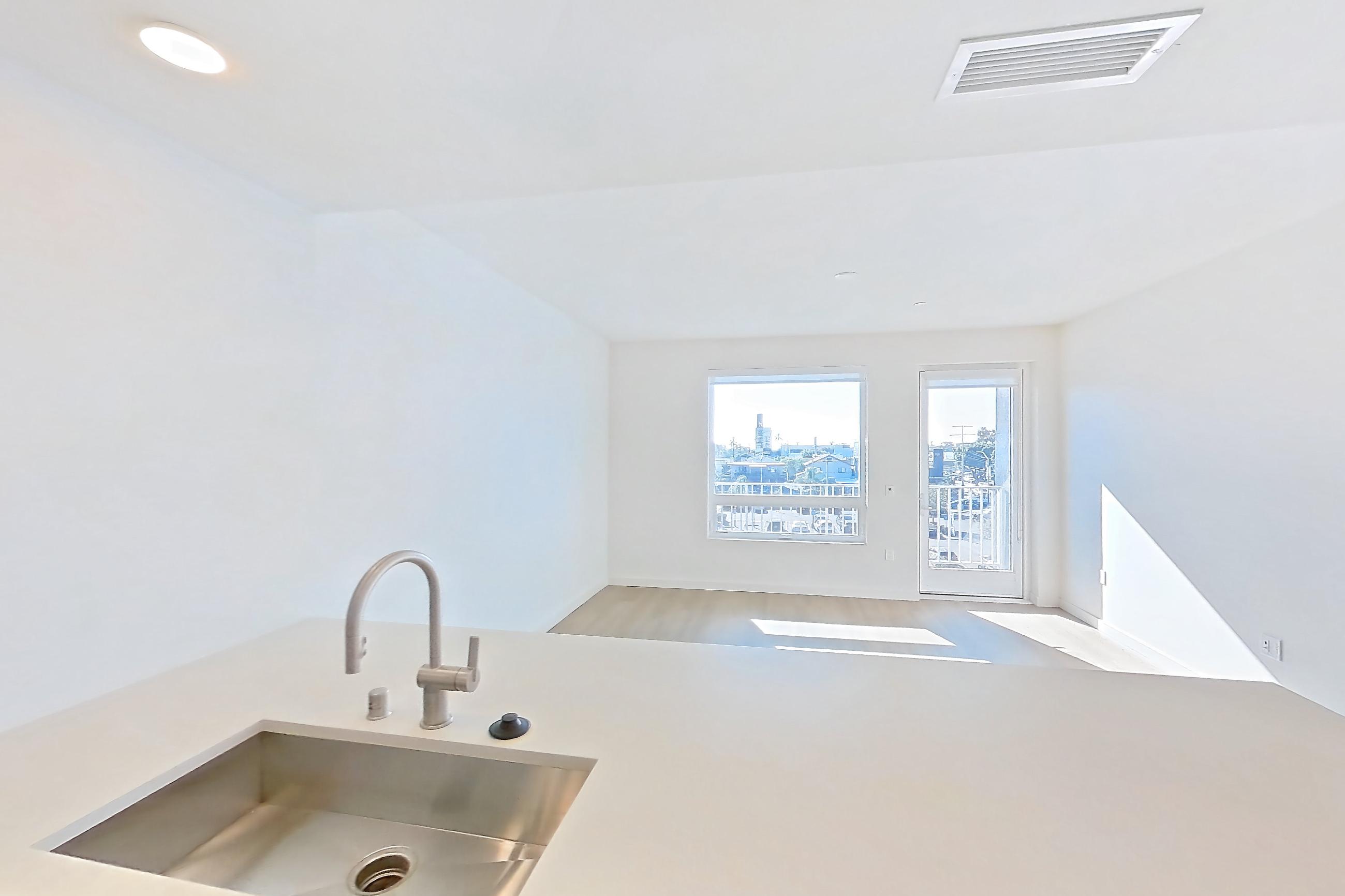 Kitchen with dishwasher, electric range, light countertops, light stone countertops, light wood-finish flooring, microwave, oven/range, refrigerator, and stainless steel appliances, Apartment 410 at Rowyn