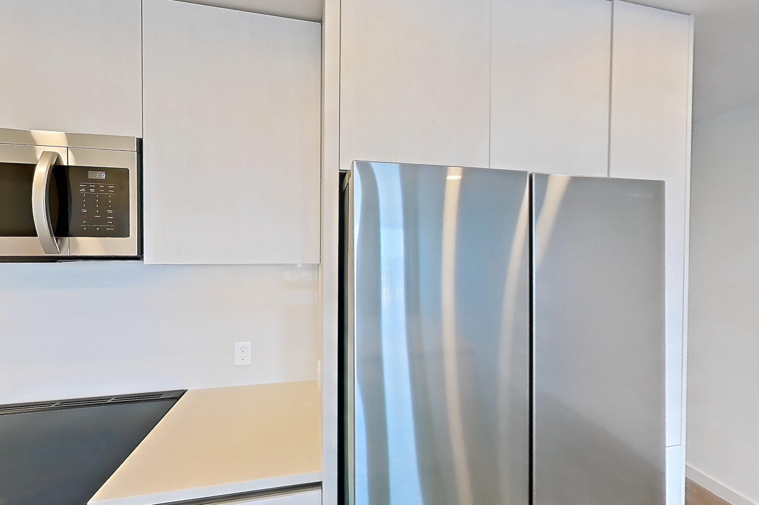 Kitchen with dishwasher, electric range, light countertops, light wood-finish flooring, microwave, oven/range, refrigerator, and stainless steel appliances, Apartment 546 at Rowyn