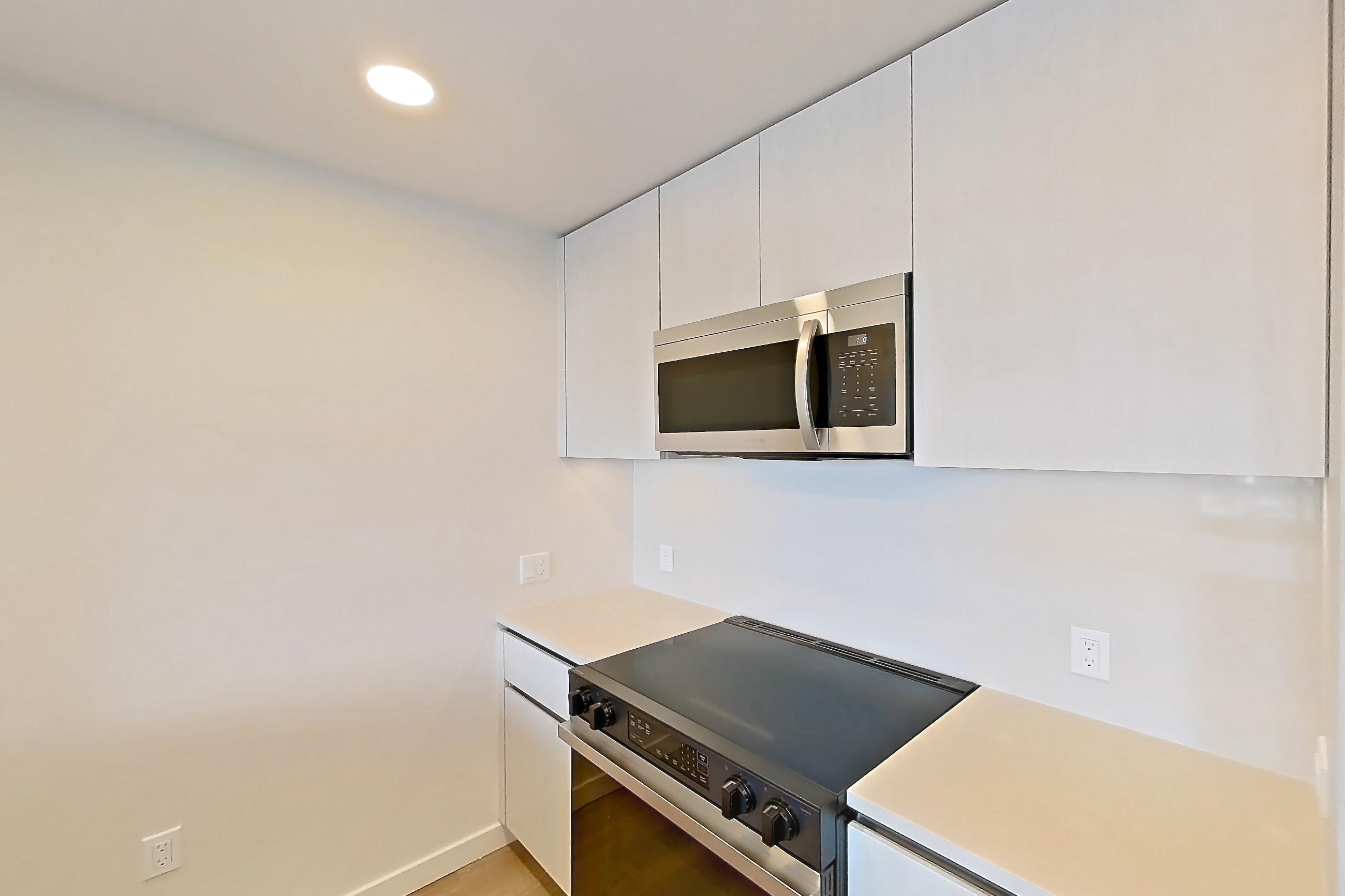 Kitchen with dishwasher, electric range, light countertops, light wood-finish flooring, microwave, oven/range, refrigerator, and stainless steel appliances, Apartment 546 at Rowyn