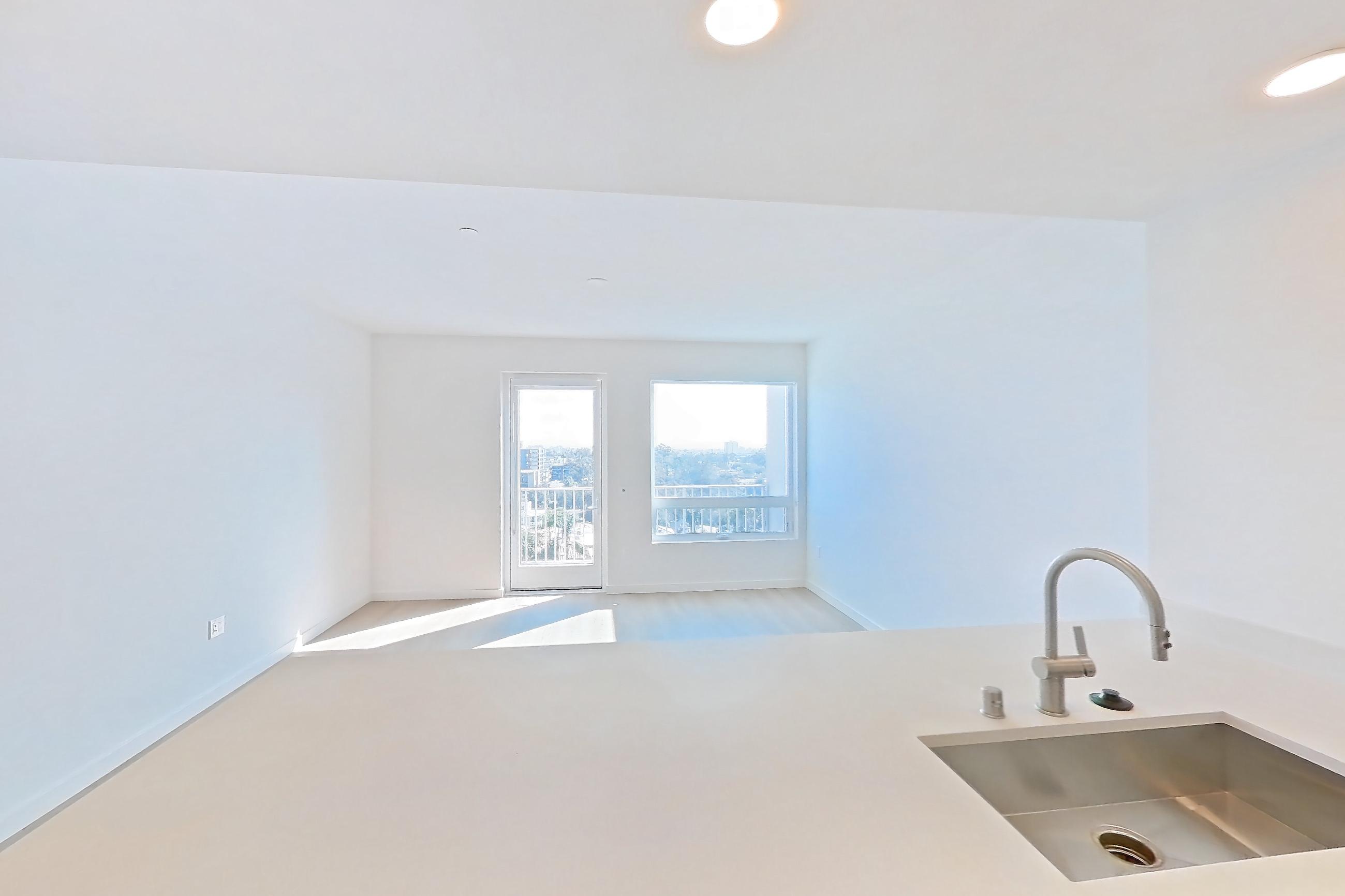 Kitchen with dishwasher, electric range, light countertops, light stone countertops, light wood-finish flooring, microwave, oven/range, refrigerator, and stainless steel appliances, Apartment 853 at Rowyn