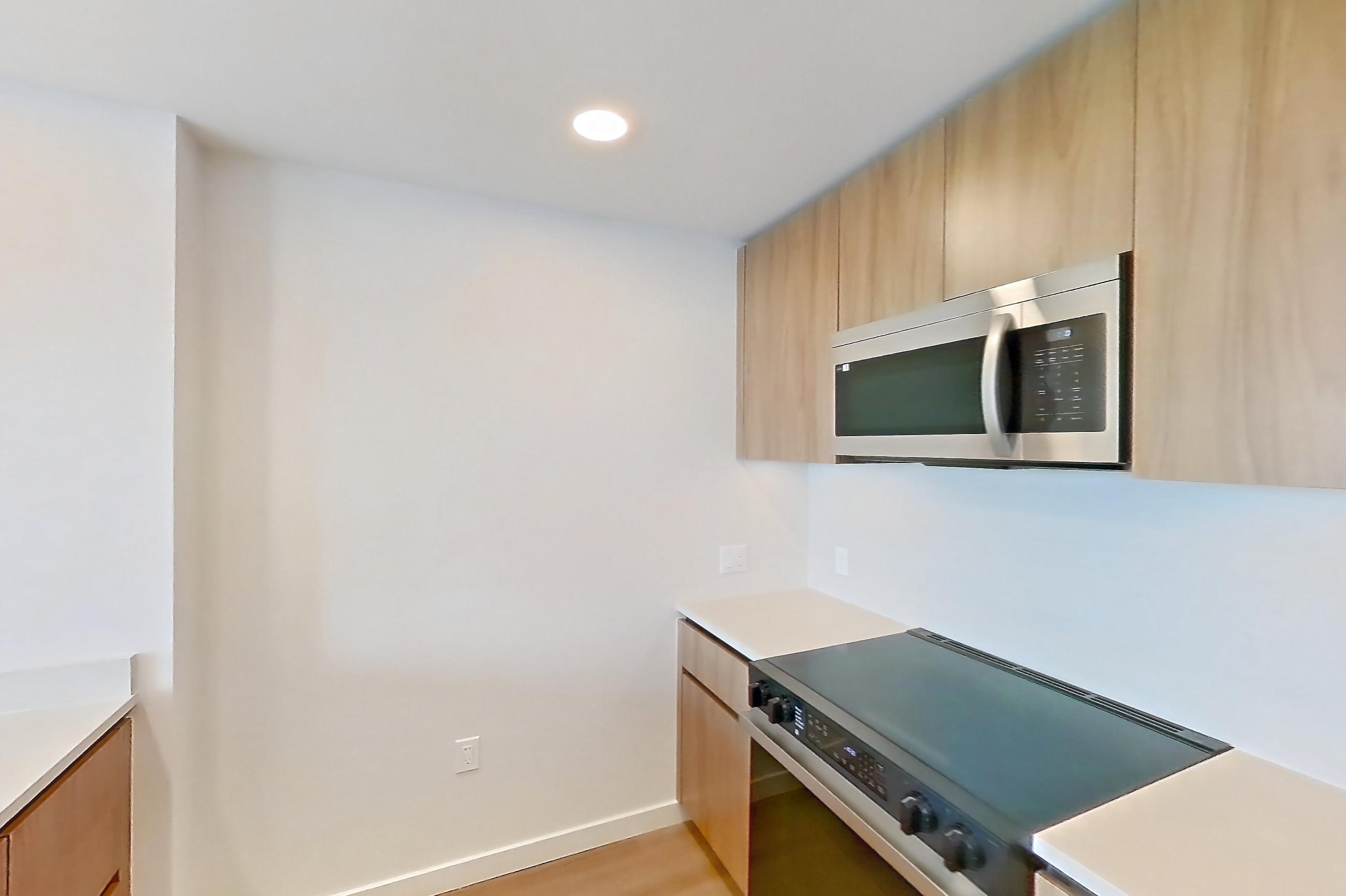 Kitchen with dishwasher, electric range, light countertops, light wood-finish flooring, microwave, oven/range, refrigerator, and stainless steel appliances, Apartment 857 at Rowyn
