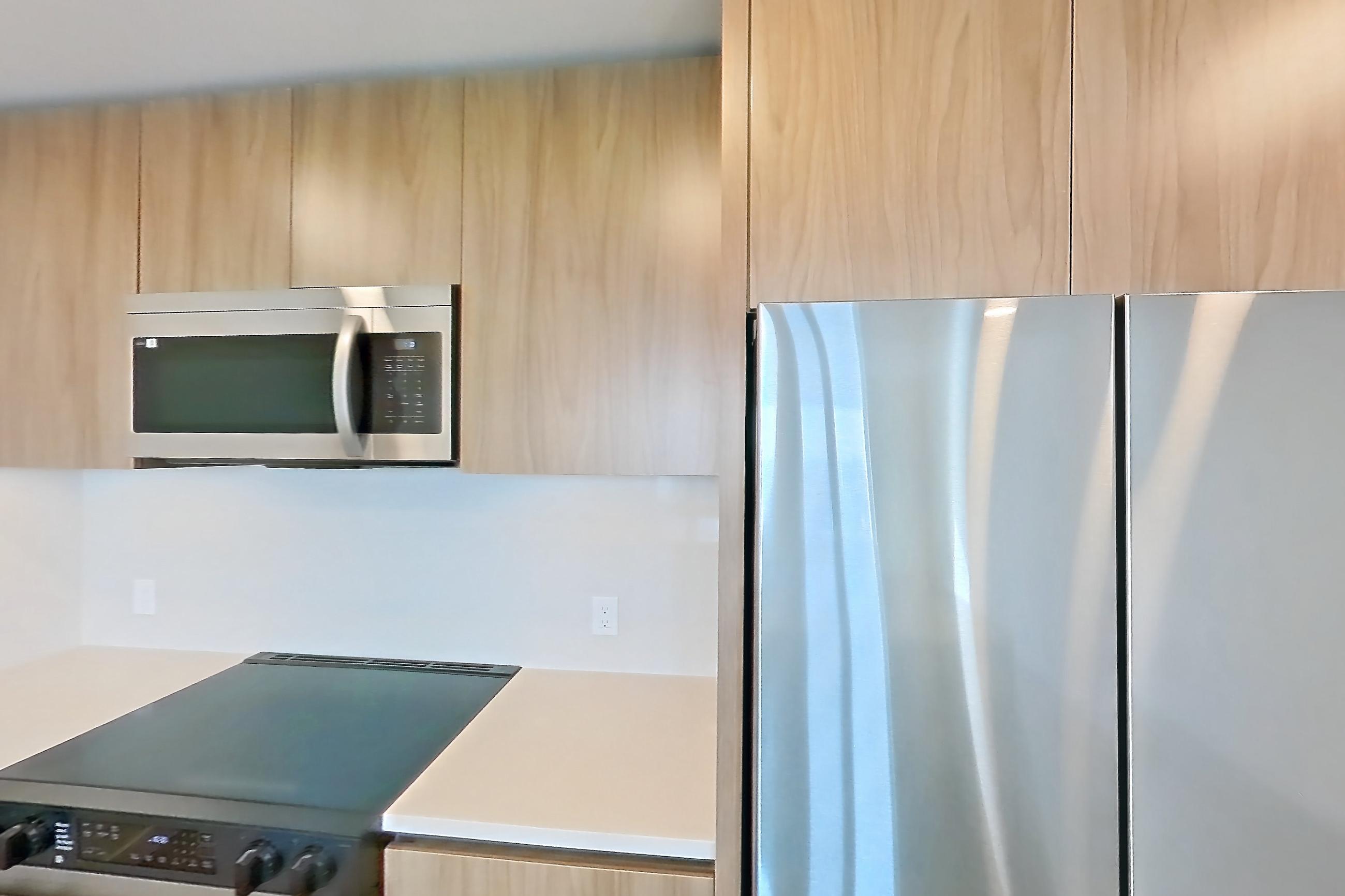 Kitchen with dishwasher, electric range, light countertops, light wood-finish flooring, microwave, oven/range, refrigerator, and stainless steel appliances, Apartment 857 at Rowyn