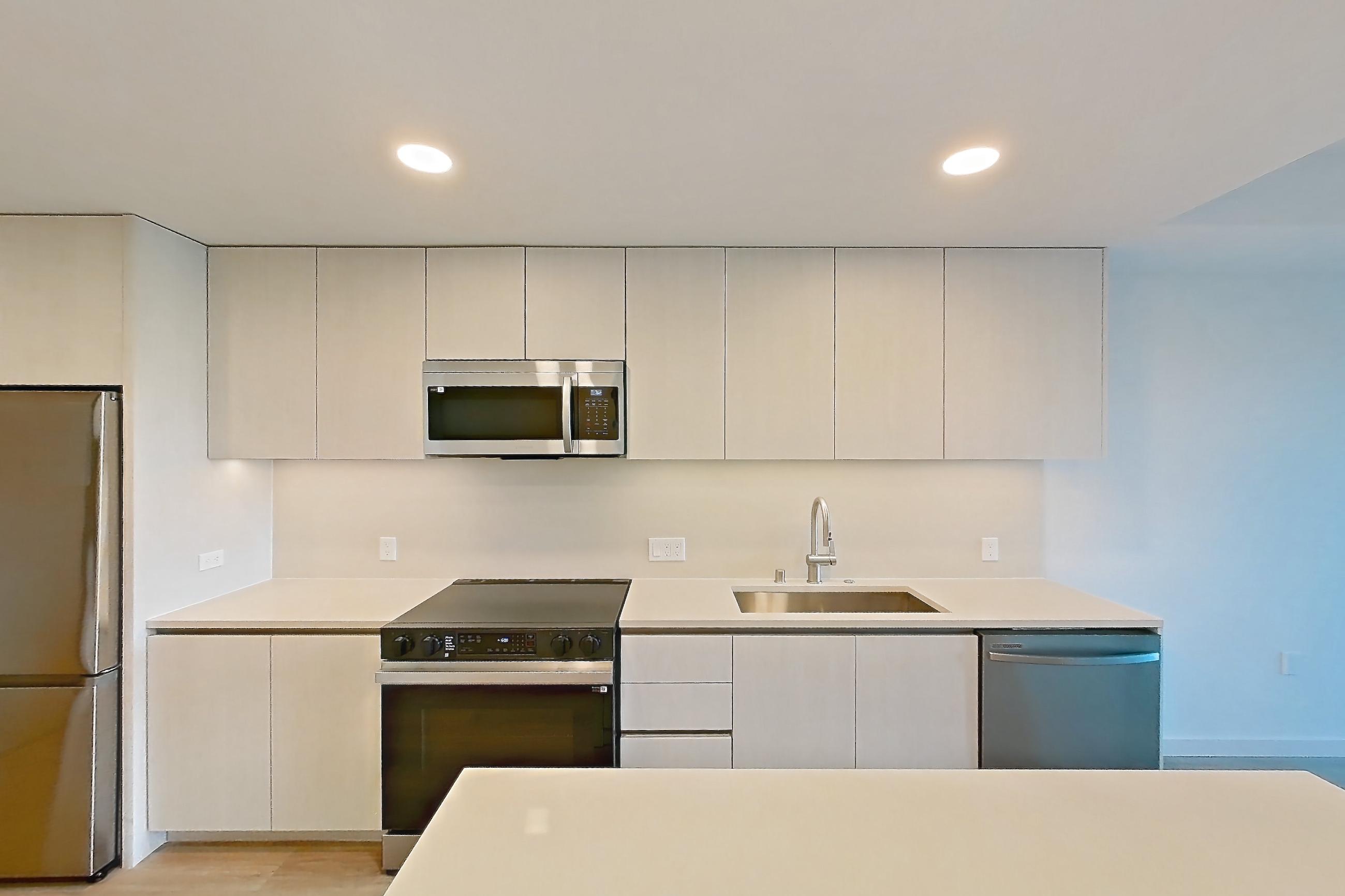 Kitchen with dishwasher, electric range, light stone countertops, light wood-finish flooring, microwave, oven/range, refrigerator, and stainless steel appliances, Apartment 343 at Rowyn
