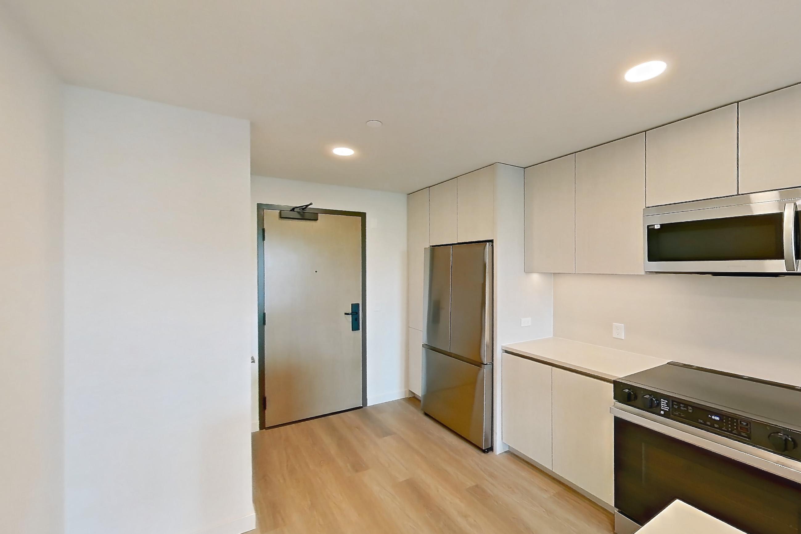 Kitchen with dishwasher, electric range, light stone countertops, light wood-finish flooring, microwave, oven/range, refrigerator, and stainless steel appliances, Apartment 343 at Rowyn