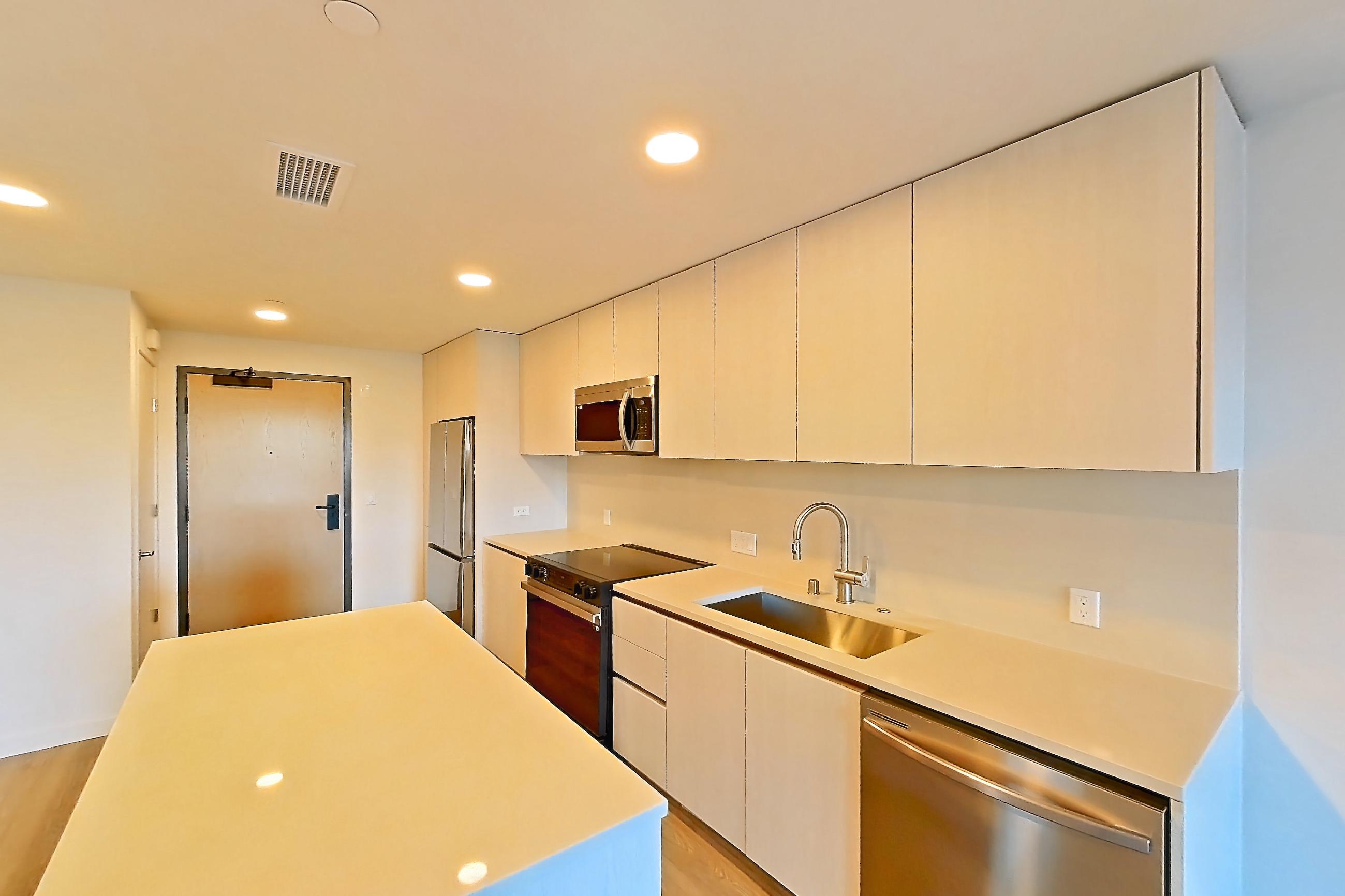 Kitchen with dishwasher, electric range, light stone countertops, light wood-finish flooring, microwave, oven/range, refrigerator, and stainless steel appliances, Apartment 351 at Rowyn