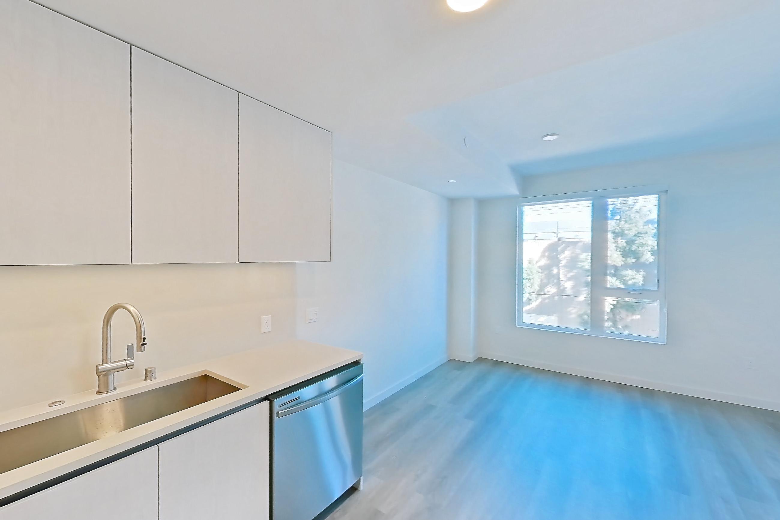 Kitchen with dishwasher, electric range, light countertops, light wood-finish flooring, microwave, oven/range, refrigerator, and stainless steel appliances, Apartment 303 at Rowyn
