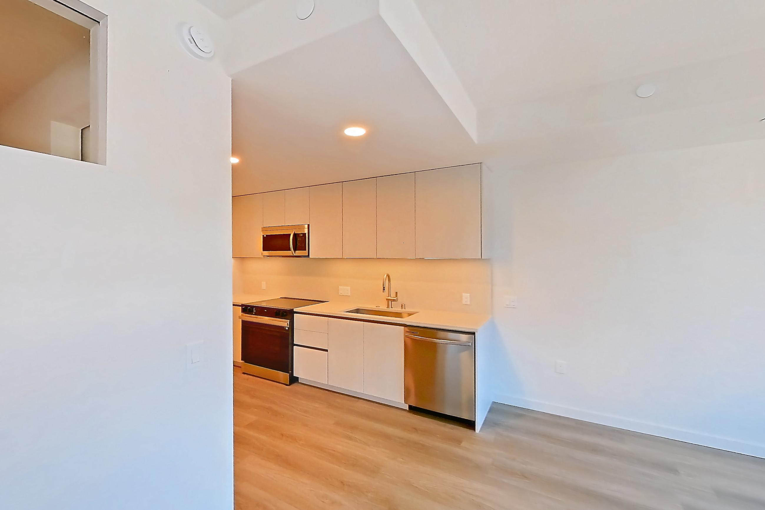 Living room with dishwasher, light countertops, light wood-finish flooring, and stainless steel appliances, Apartment 303 at Rowyn