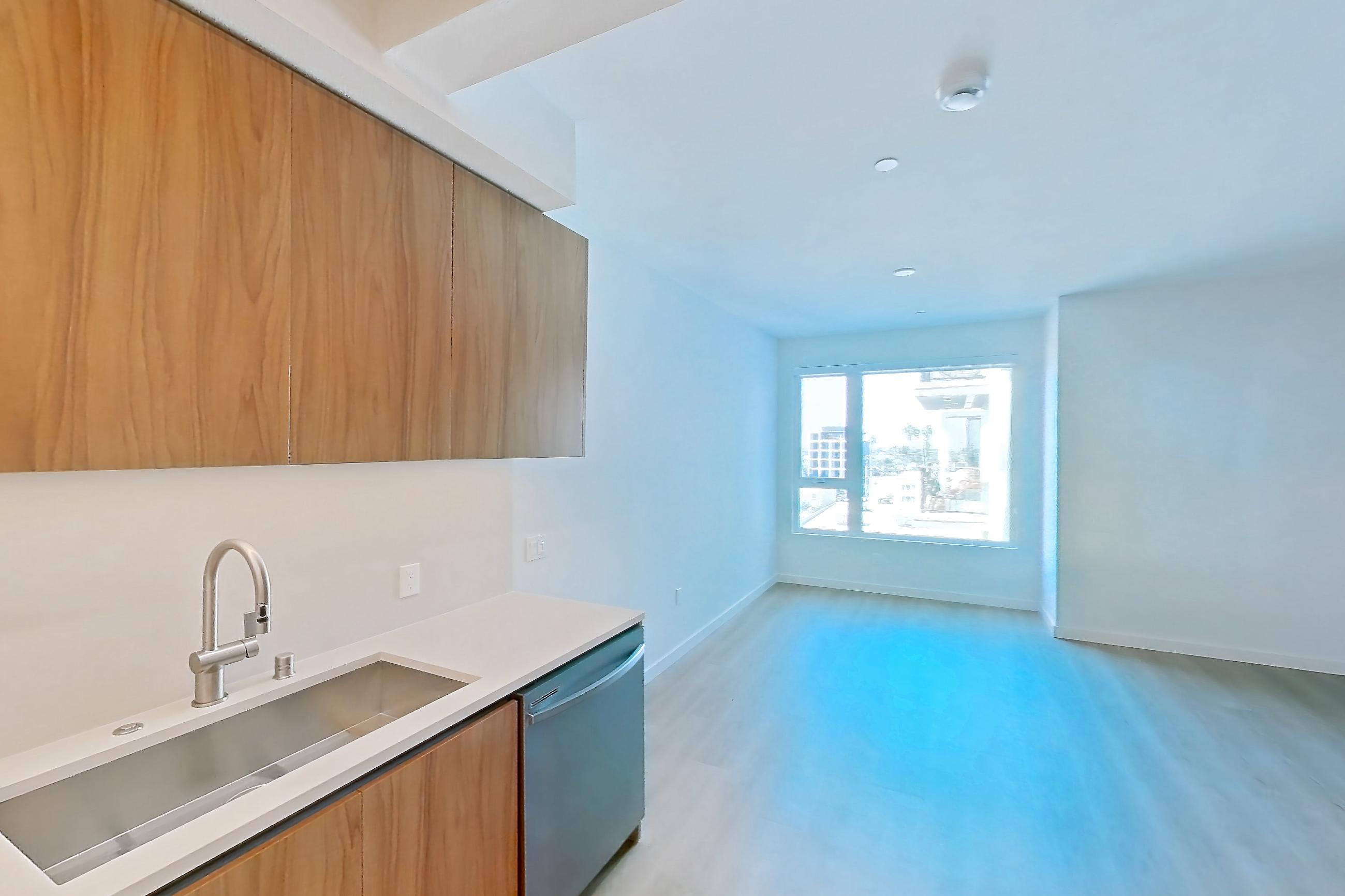 Kitchen with dishwasher, electric range, light countertops, light wood-finish flooring, microwave, oven/range, refrigerator, and stainless steel appliances, Apartment 622 at Rowyn
