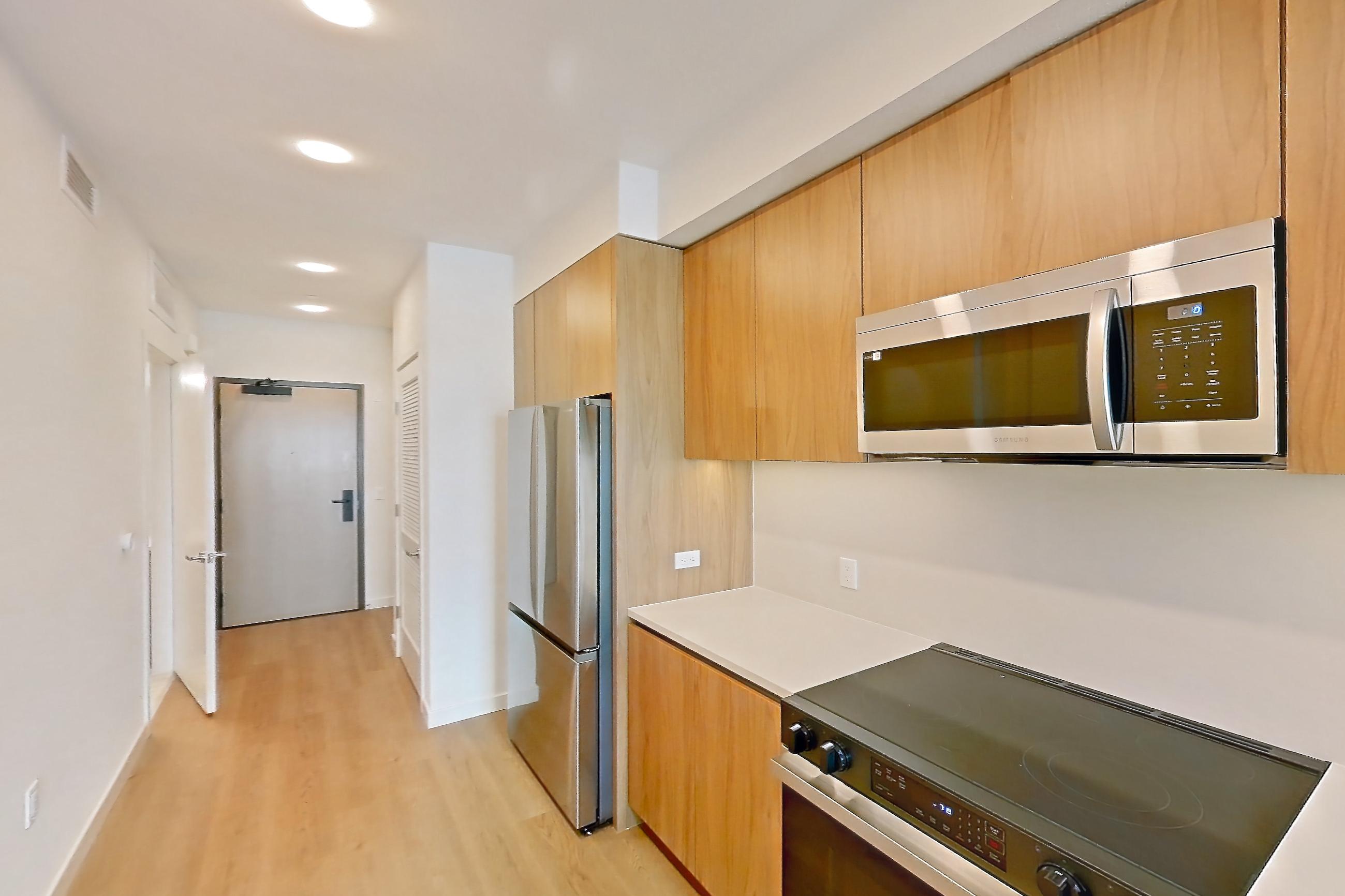 Kitchen with dishwasher, electric range, light countertops, light wood-finish flooring, microwave, oven/range, refrigerator, and stainless steel appliances, Apartment 622 at Rowyn