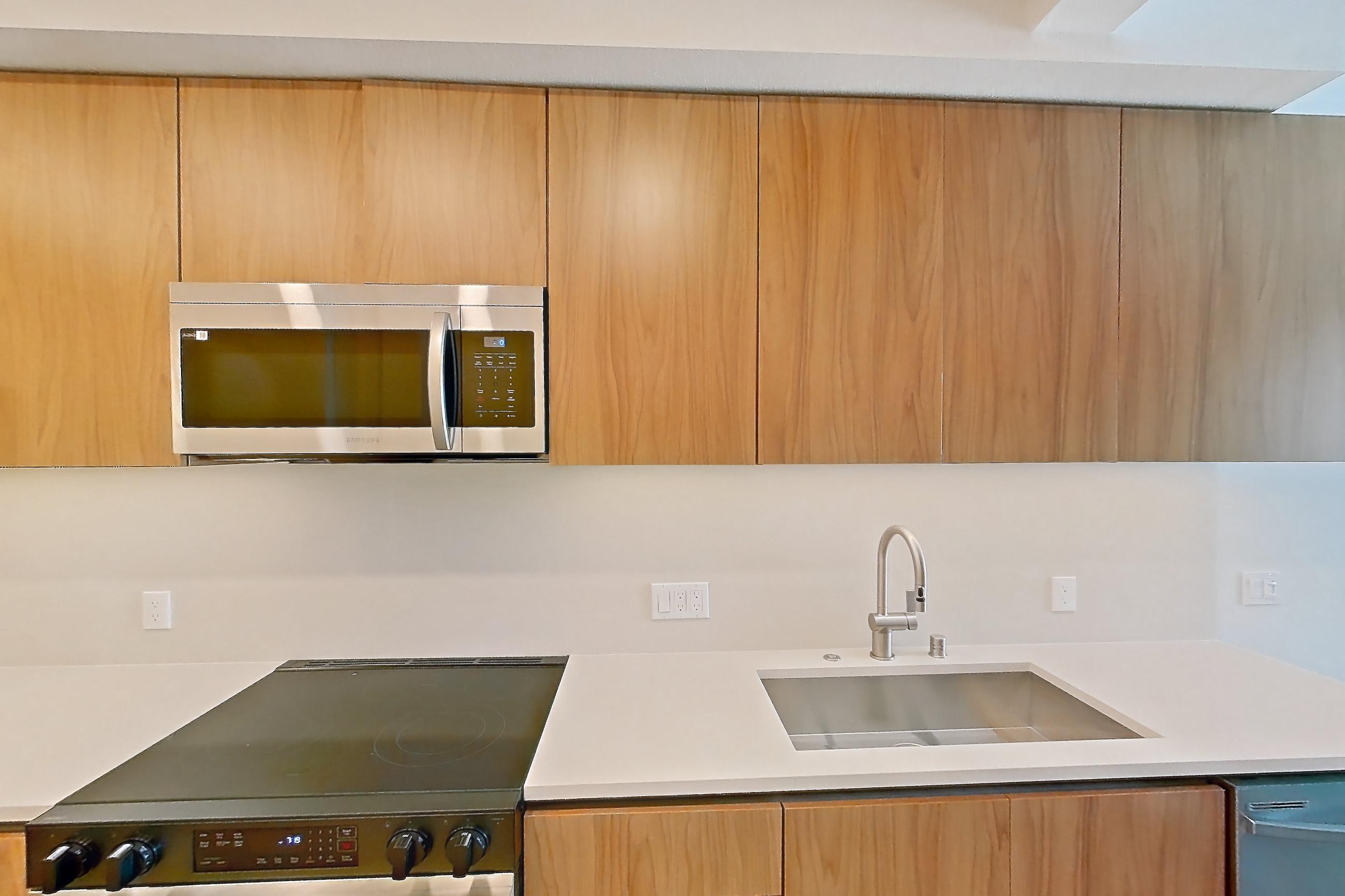 Kitchen with dishwasher, electric range, light countertops, light wood-finish flooring, microwave, oven/range, refrigerator, and stainless steel appliances, Apartment 622 at Rowyn