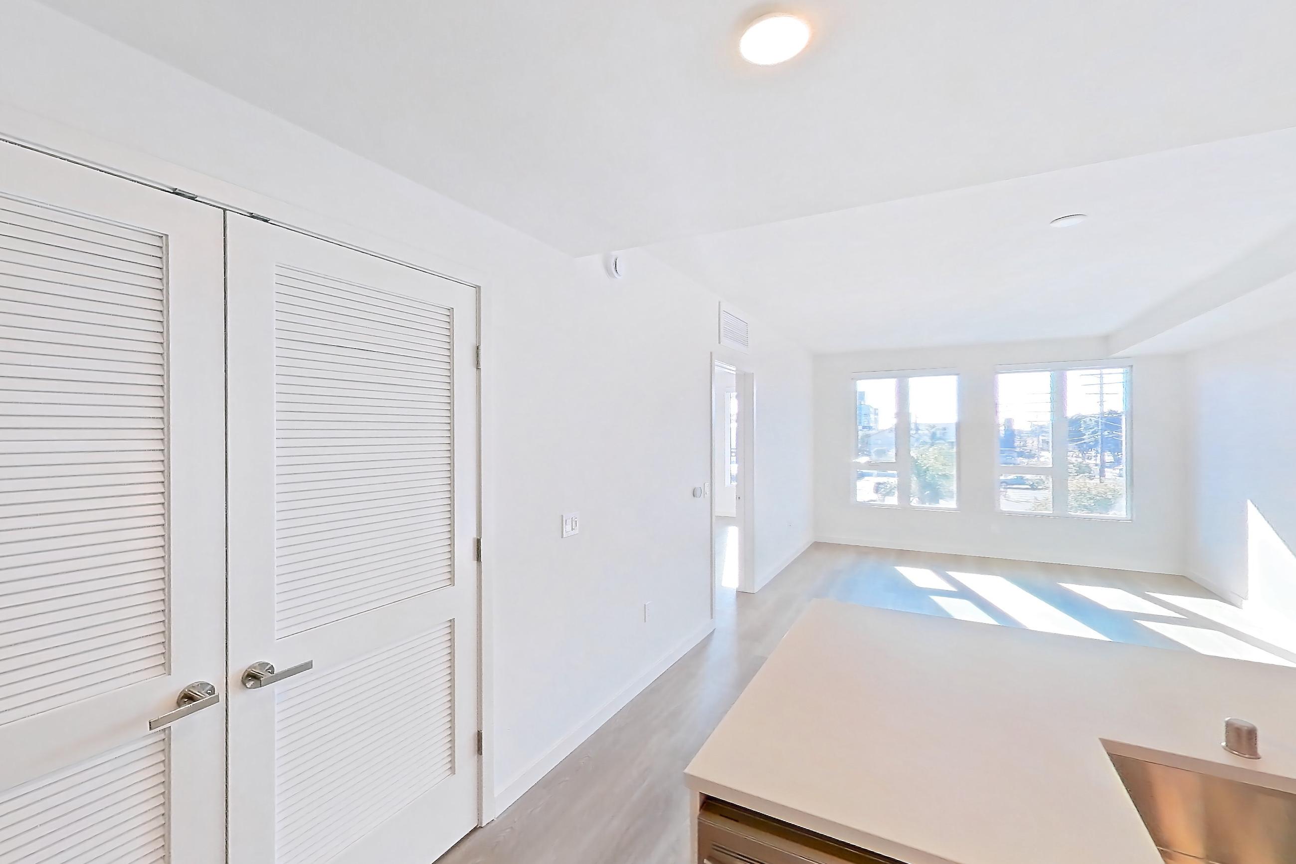 Kitchen with dishwasher, electric range, kitchen island, light countertops, light stone countertops, light wood-finish flooring, microwave, oven/range, refrigerator, and stainless steel appliances, Apartment 305 at Rowyn