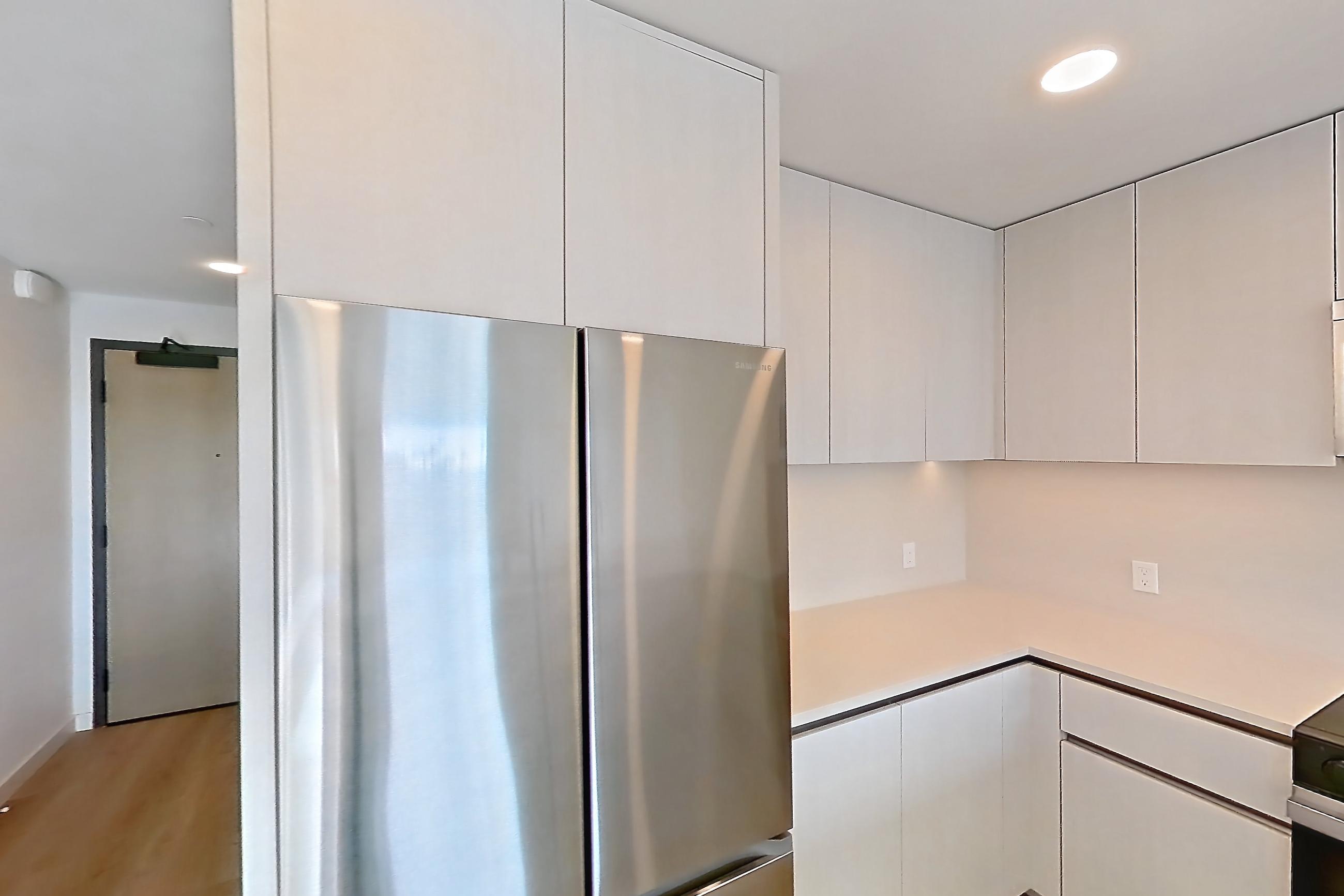 Kitchen with dishwasher, electric range, light countertops, light stone countertops, light wood-finish flooring, microwave, oven/range, refrigerator, and stainless steel appliances, Apartment 344 at Rowyn