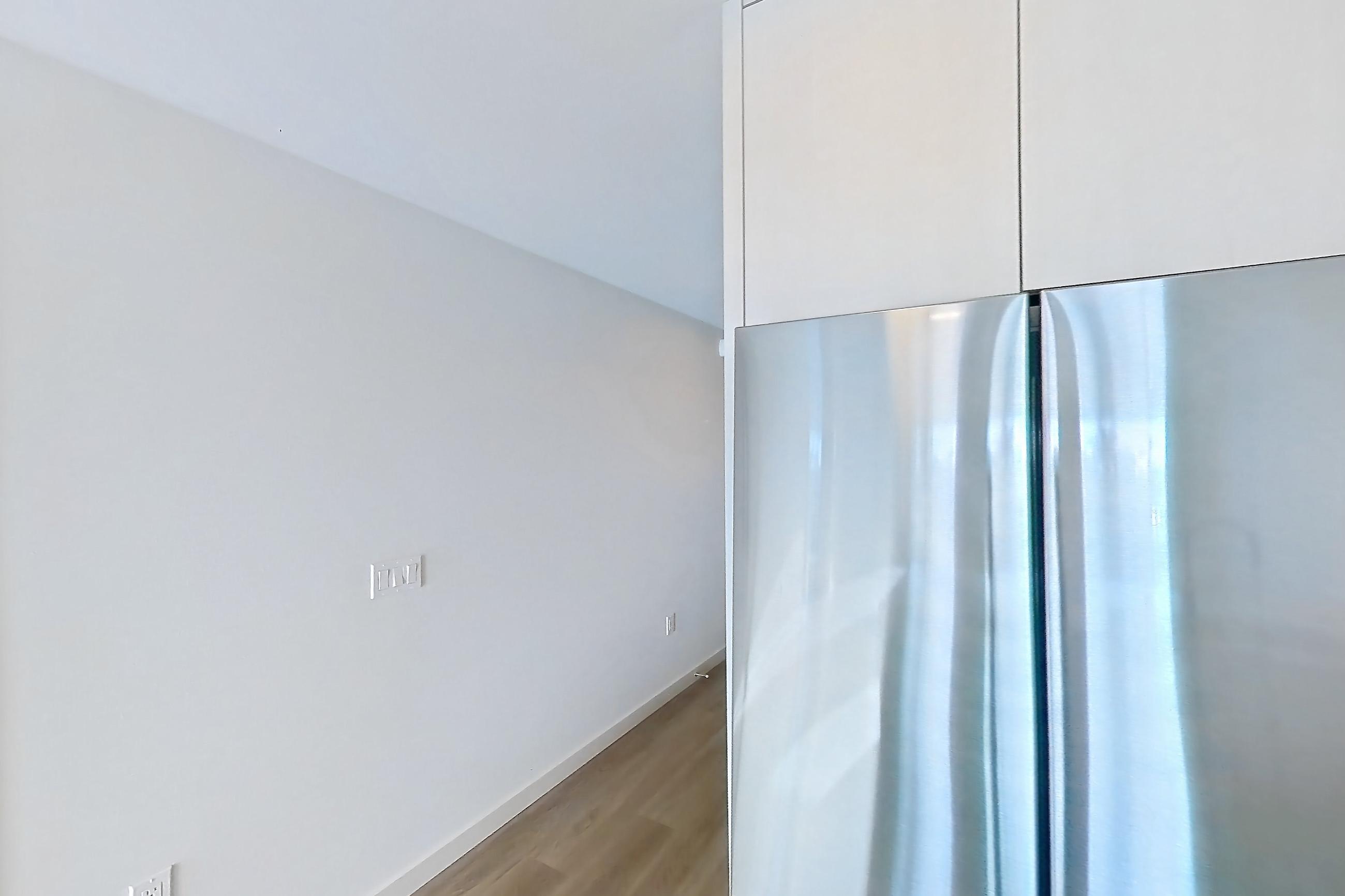 Kitchen with dishwasher, electric range, kitchen island, light countertops, light stone countertops, light wood-finish flooring, microwave, oven/range, refrigerator, and stainless steel appliances, Apartment 348 at Rowyn
