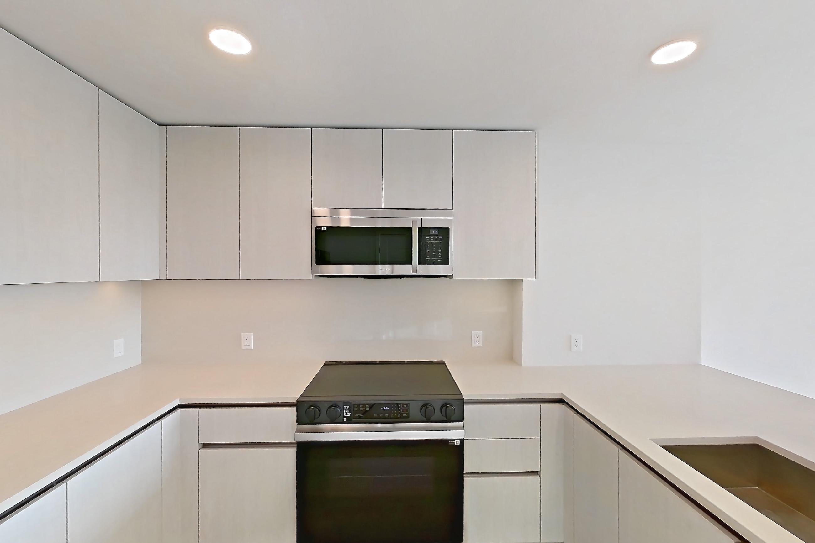 Kitchen with dishwasher, electric range, light countertops, light stone countertops, light wood-finish flooring, microwave, oven/range, refrigerator, and stainless steel appliances, Apartment 356 at Rowyn