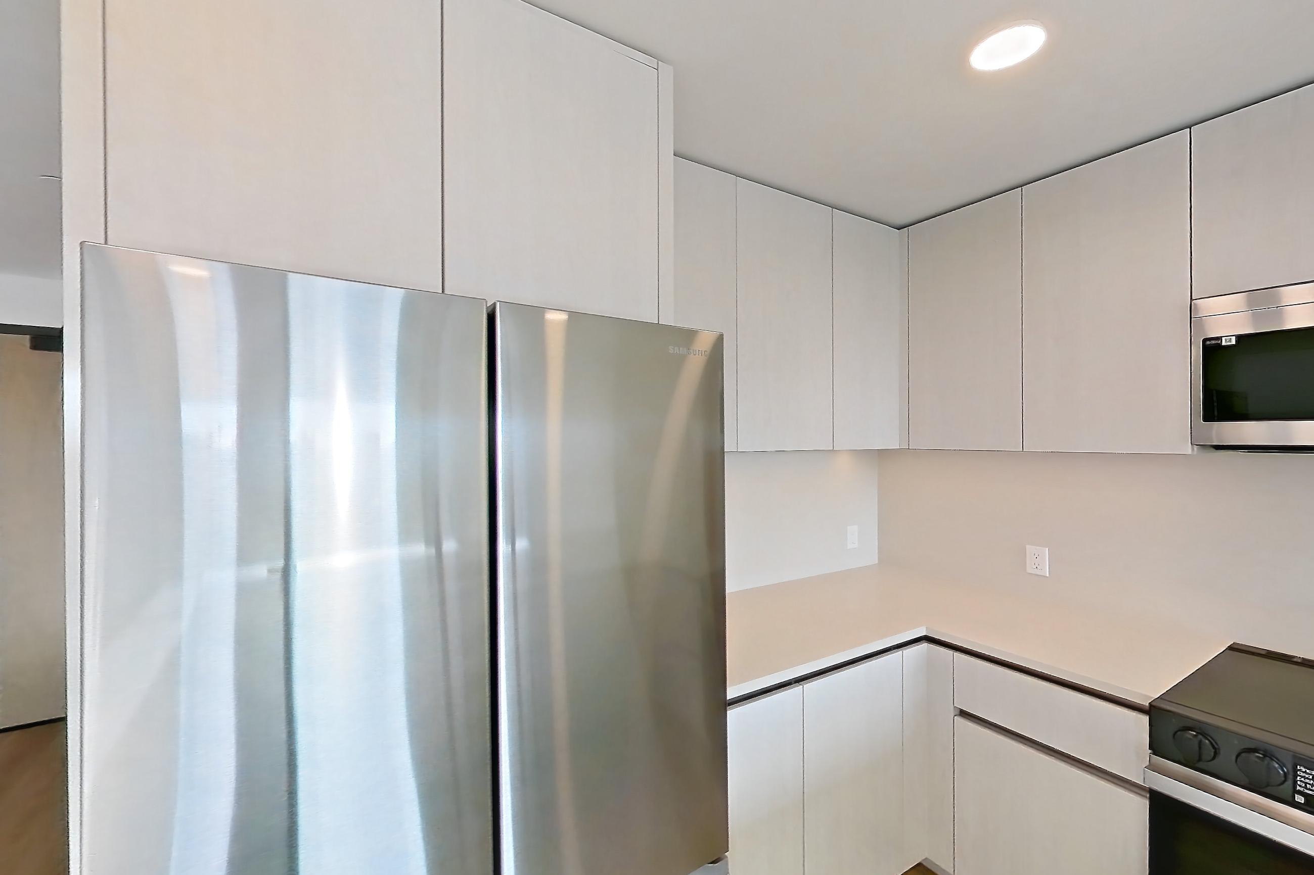 Kitchen with dishwasher, electric range, light countertops, light stone countertops, light wood-finish flooring, microwave, oven/range, refrigerator, and stainless steel appliances, Apartment 356 at Rowyn