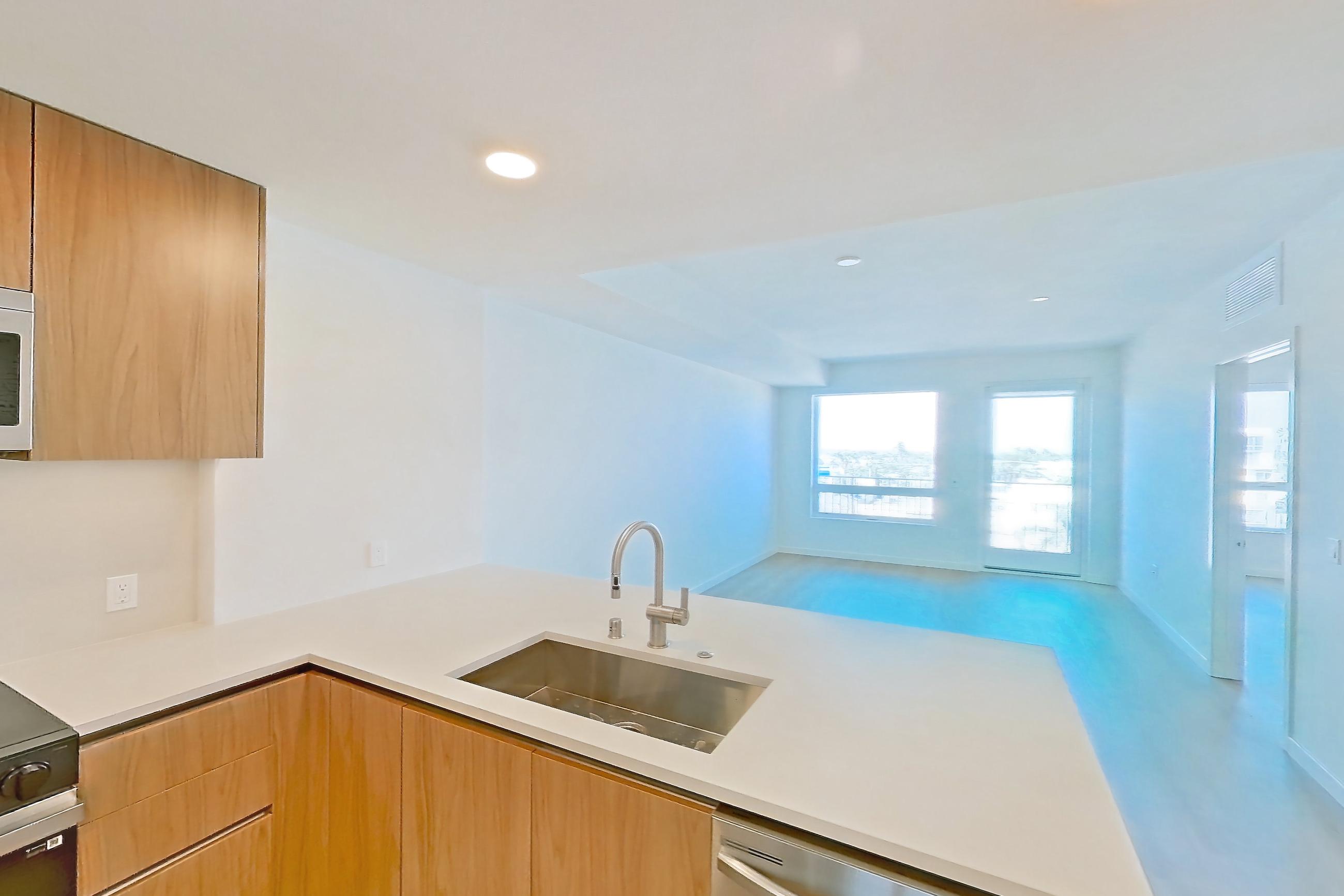 Kitchen with dishwasher, electric range, light countertops, light stone countertops, light wood-finish flooring, microwave, oven/range, refrigerator, and stainless steel appliances, Apartment 652 at Rowyn