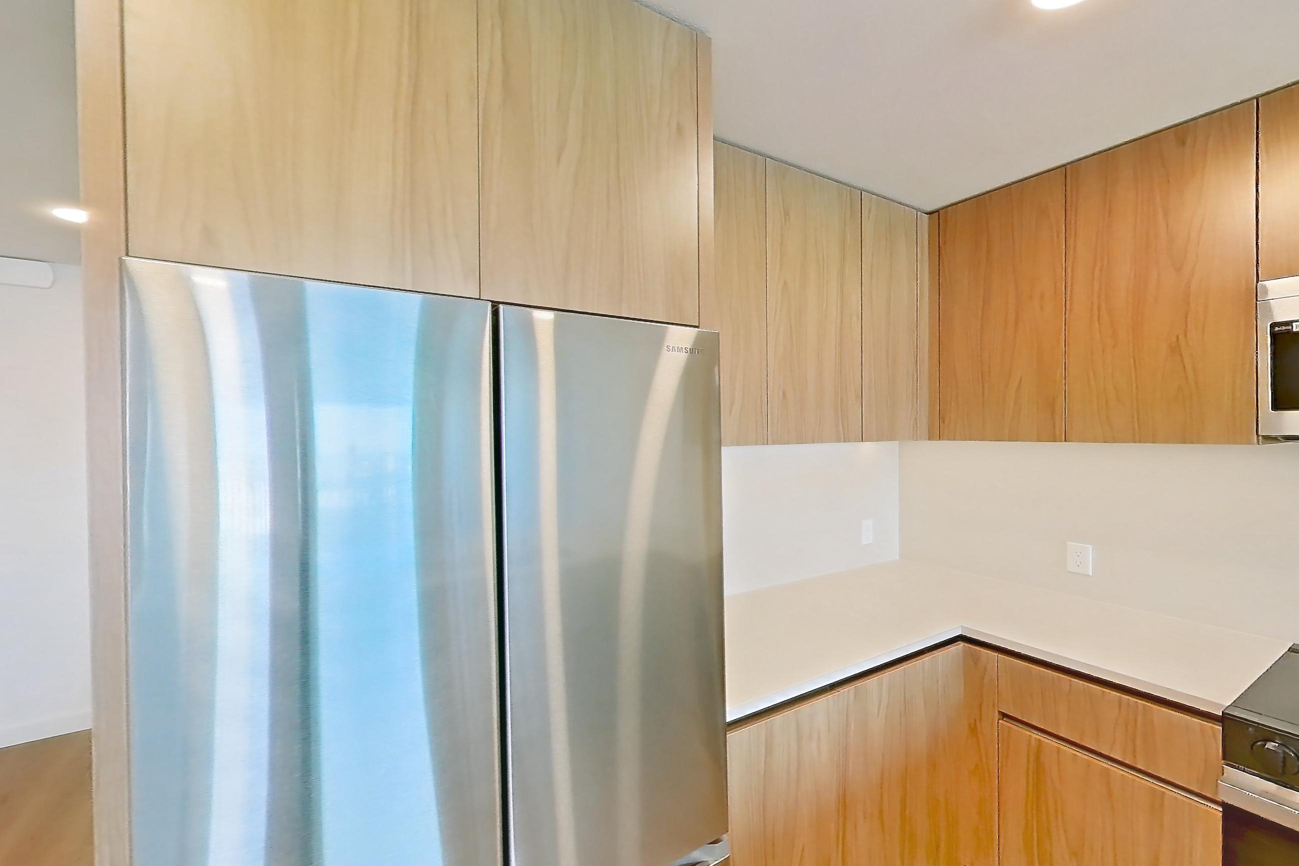 Kitchen with dishwasher, electric range, light countertops, light stone countertops, light wood-finish flooring, microwave, oven/range, refrigerator, and stainless steel appliances, Apartment 652 at Rowyn