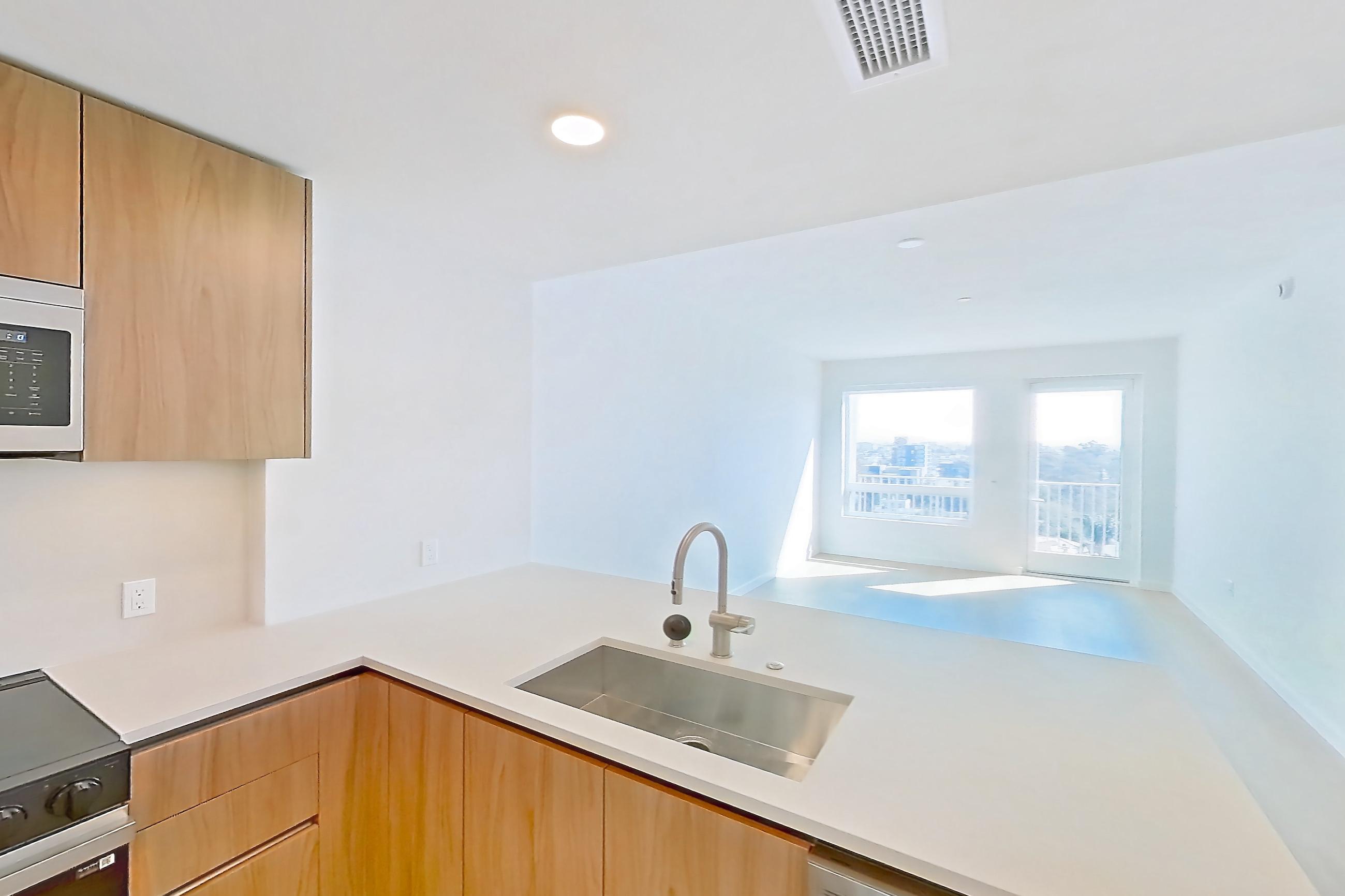 Kitchen with dishwasher, electric range, kitchen island, light countertops, light stone countertops, light wood-finish flooring, microwave, oven/range, and stainless steel appliances, Apartment 855 at Rowyn