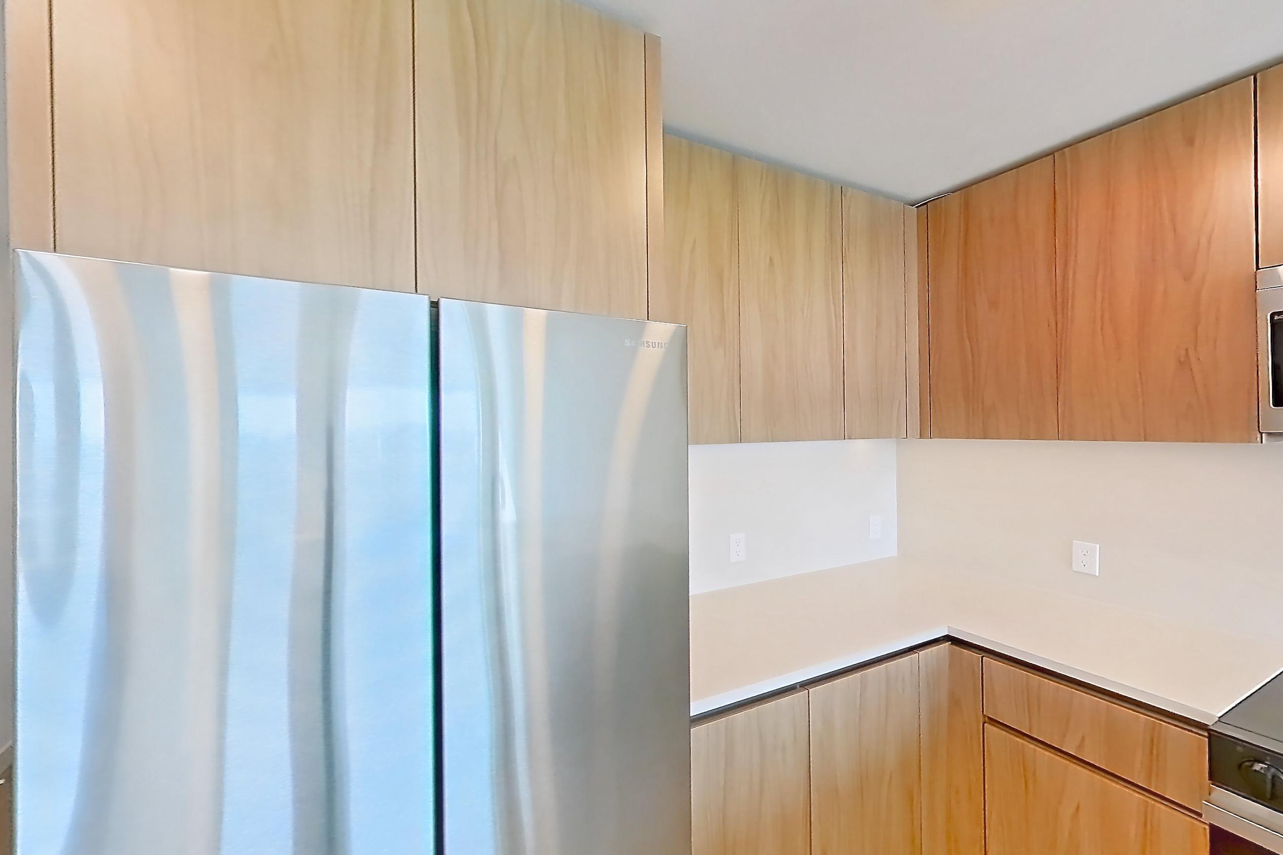 Kitchen with dishwasher, electric range, kitchen island, light countertops, light stone countertops, light wood-finish flooring, microwave, oven/range, and stainless steel appliances, Apartment 855 at Rowyn
