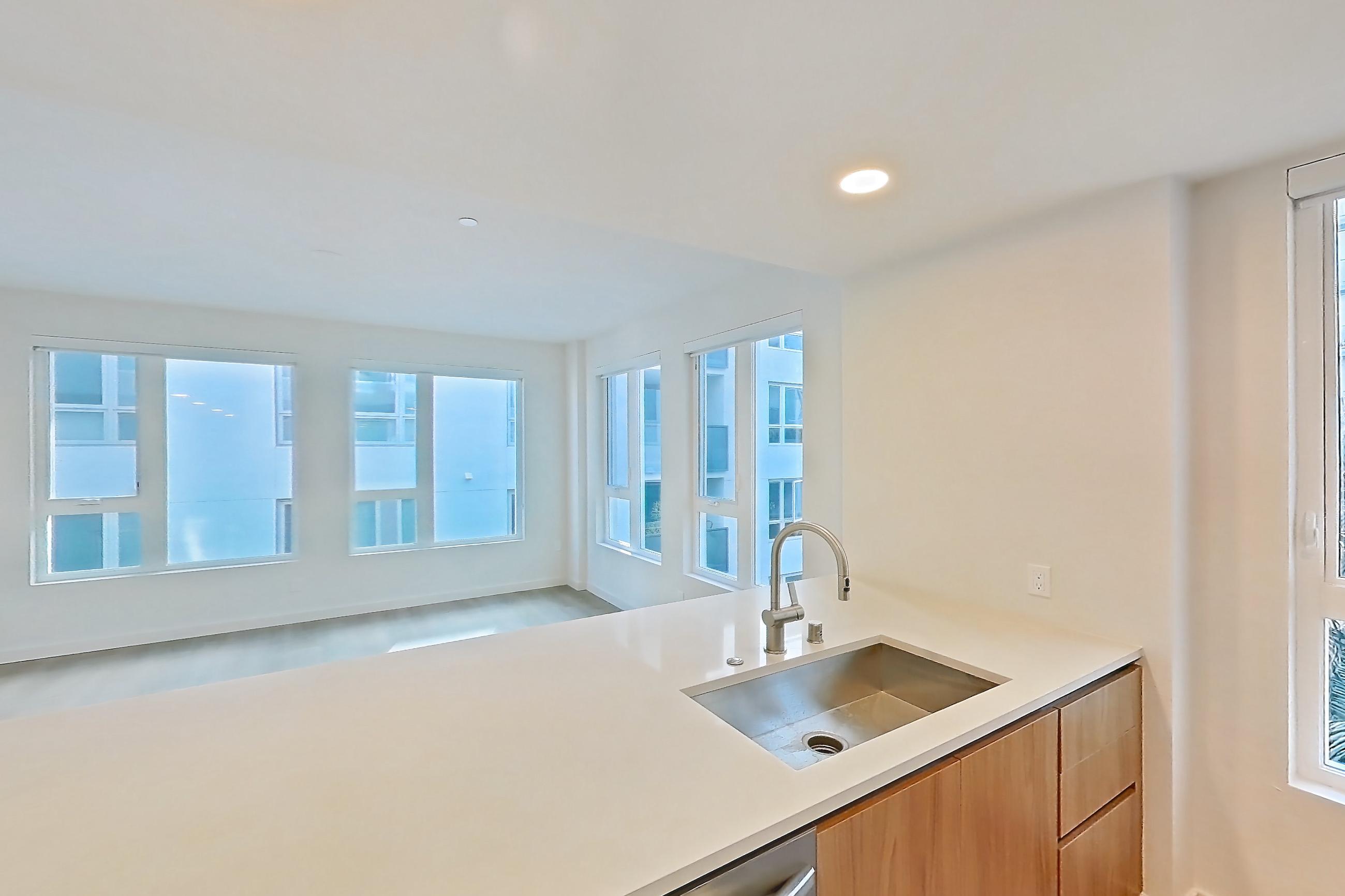 Kitchen with black appliances, dishwasher, electric range, light countertops, light wood-finish flooring, microwave, oven/range, refrigerator, and stainless steel appliances, Apartment 401 at Rowyn