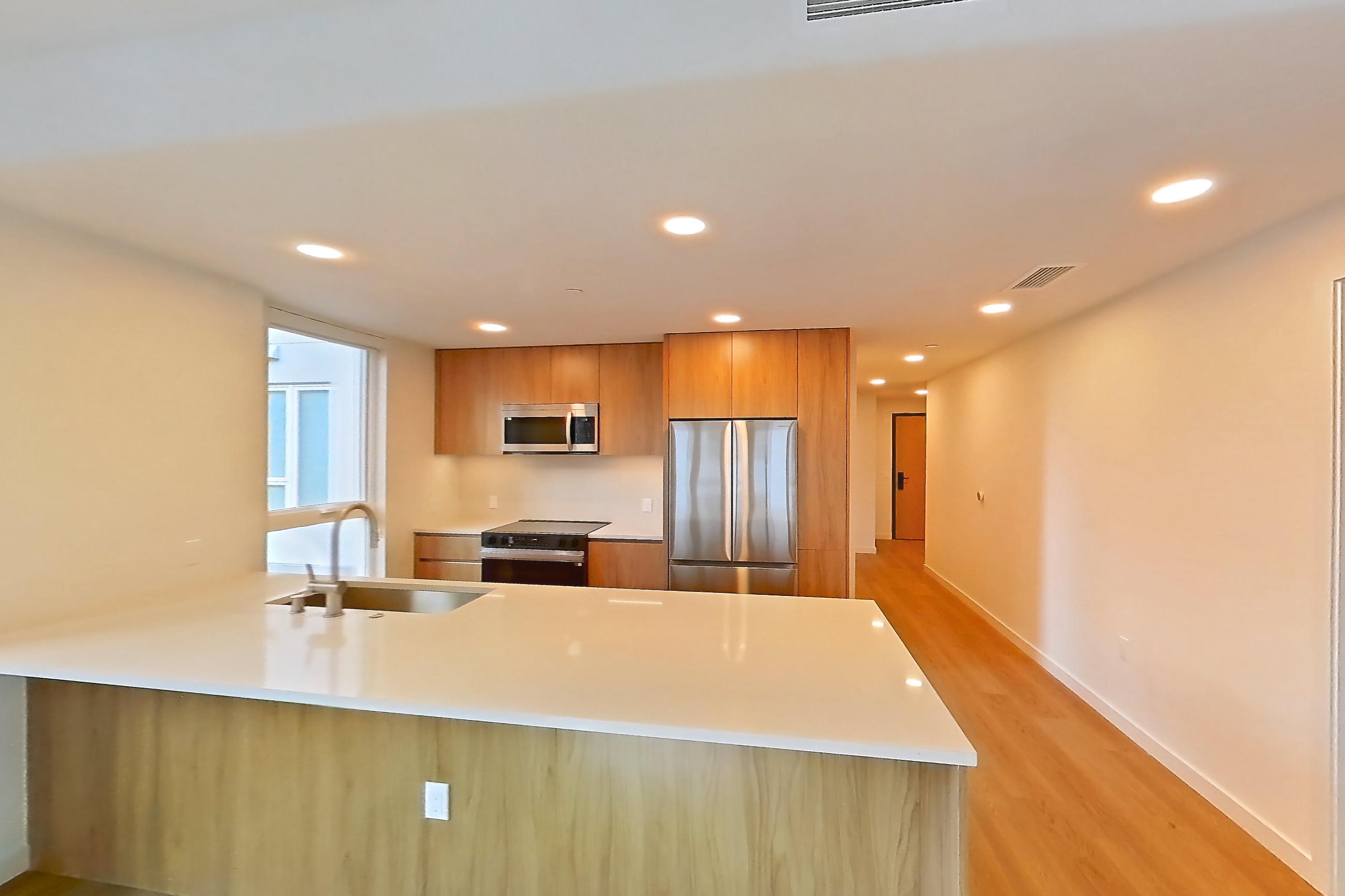 Living room with electric range, light stone countertops, light wood-finish flooring, oven/range, refrigerator, and stainless steel appliances, Apartment 401 at Rowyn