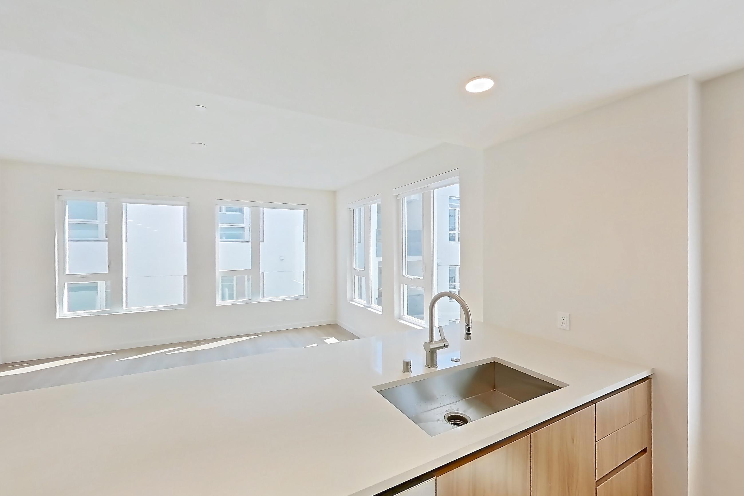 Kitchen with dishwasher, electric range, light countertops, light stone countertops, light wood-finish flooring, oven/range, refrigerator, and stainless steel appliances, Apartment 601 at Rowyn
