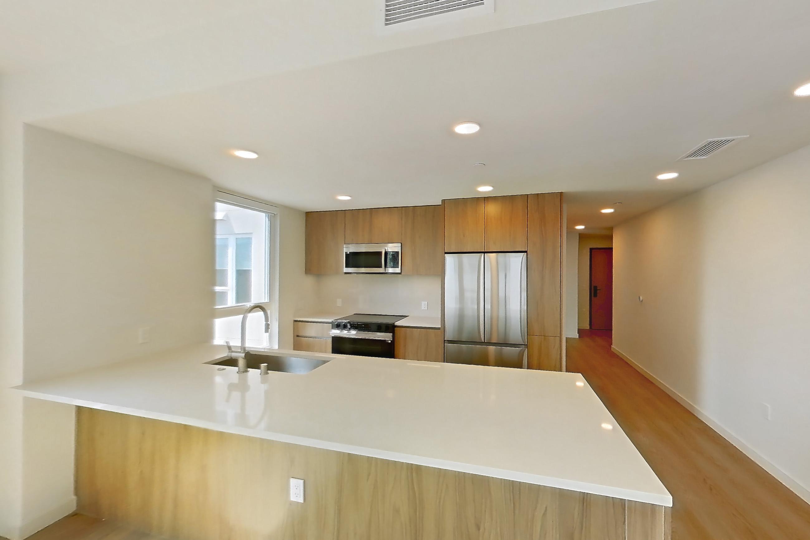 Living room with electric range, light countertops, light wood-finish flooring, oven/range, refrigerator, and stainless steel appliances, Apartment 601 at Rowyn