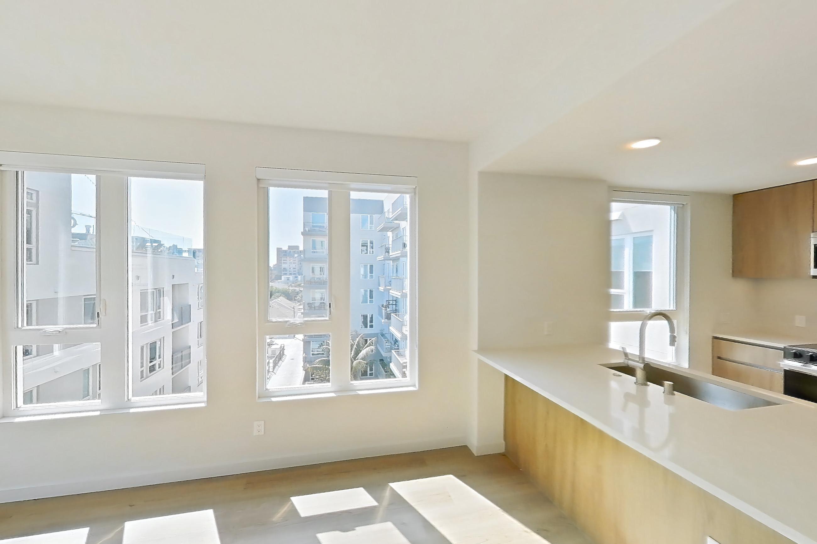 Living room with electric range, light countertops, light wood-finish flooring, oven/range, refrigerator, and stainless steel appliances, Apartment 601 at Rowyn
