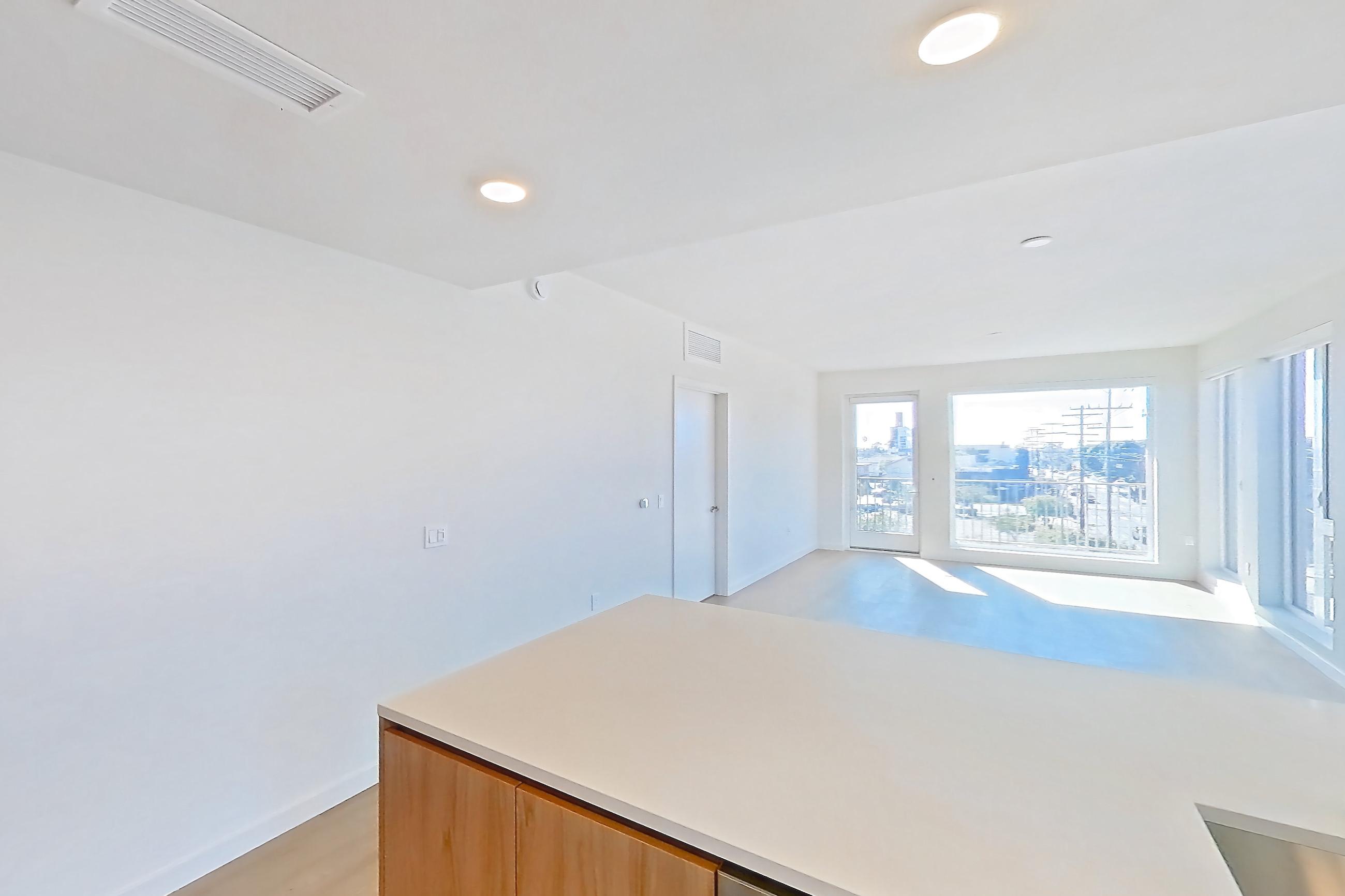 Kitchen with dishwasher, electric range, kitchen island, light countertops, light stone countertops, light wood-finish flooring, microwave, oven/range, refrigerator, and stainless steel appliances, Apartment 404 at Rowyn
