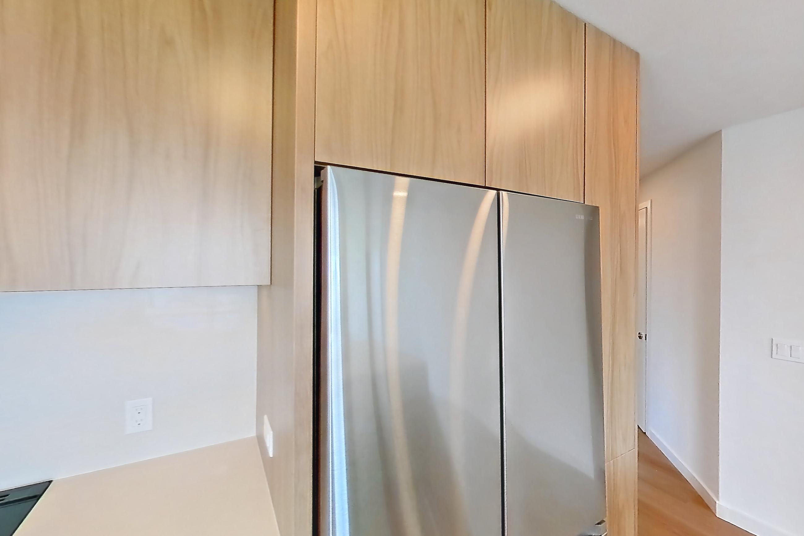Kitchen with dishwasher, electric range, kitchen island, light countertops, light stone countertops, light wood-finish flooring, microwave, oven/range, refrigerator, and stainless steel appliances, Apartment 404 at Rowyn