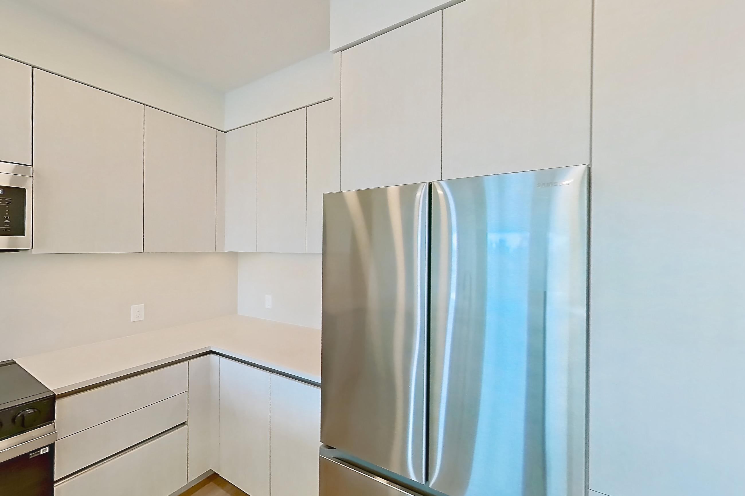 Kitchen with dishwasher, electric range, light countertops, light stone countertops, light wood-finish flooring, microwave, oven/range, refrigerator, and stainless steel appliances, Apartment 339 at Rowyn