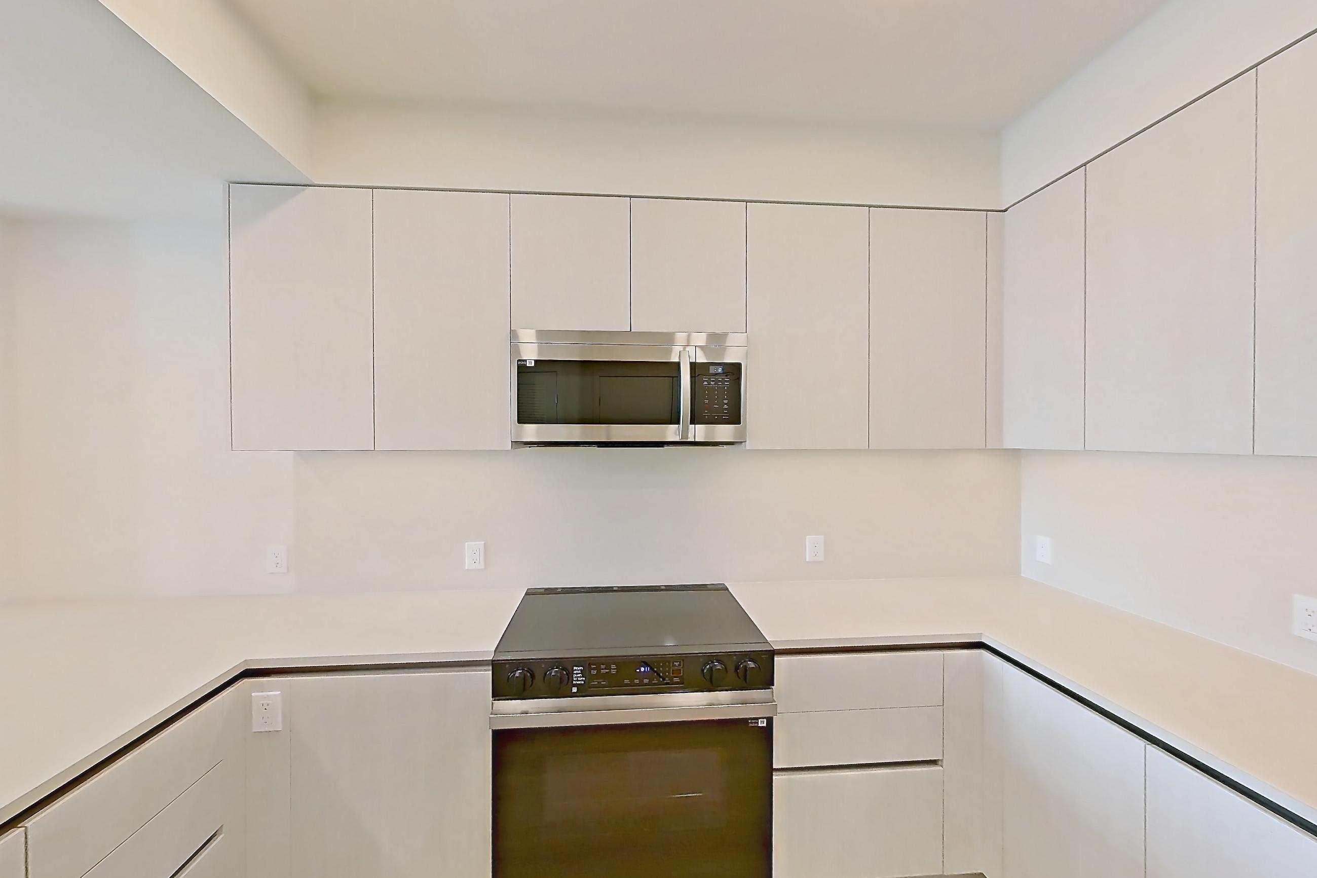 Kitchen with dishwasher, electric range, light countertops, light wood-finish flooring, microwave, oven/range, refrigerator, and stainless steel appliances, Apartment 739 at Rowyn