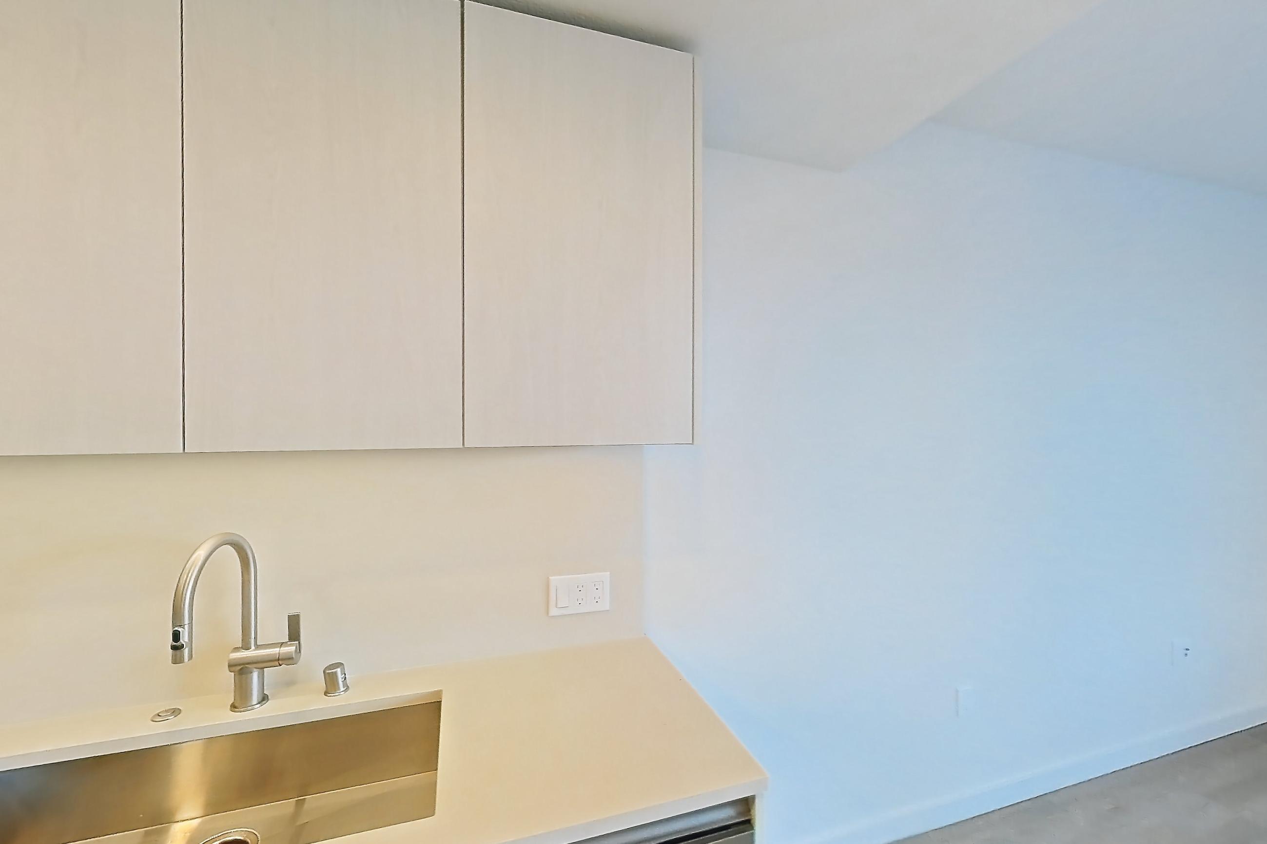 Kitchen with black appliances, dishwasher, electric range, light countertops, light wood-finish flooring, microwave, oven/range, refrigerator, and stainless steel appliances, Apartment 329 at Rowyn